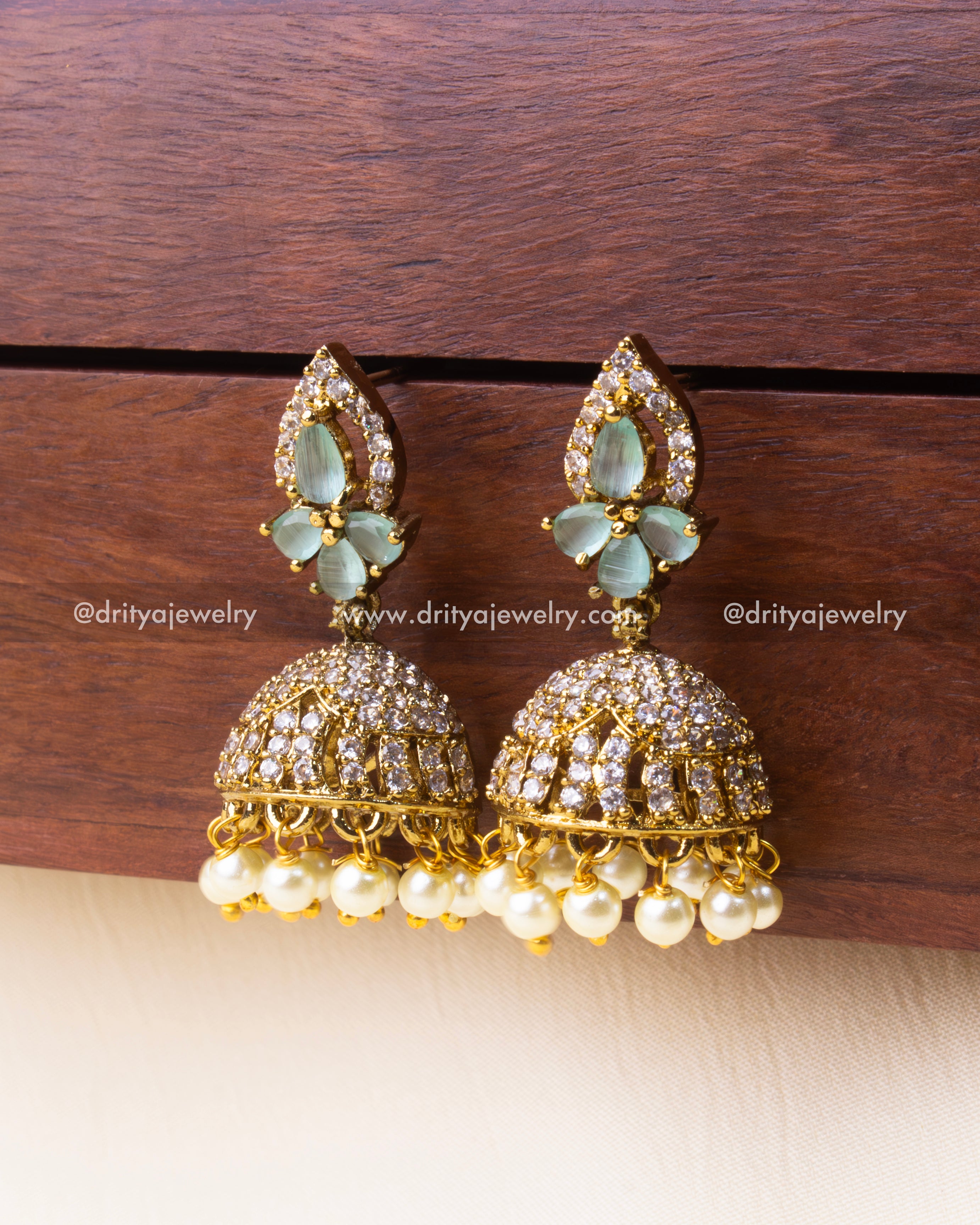 Mint-colored CZ Jhumka earrings with pearl drops and golden finish.
