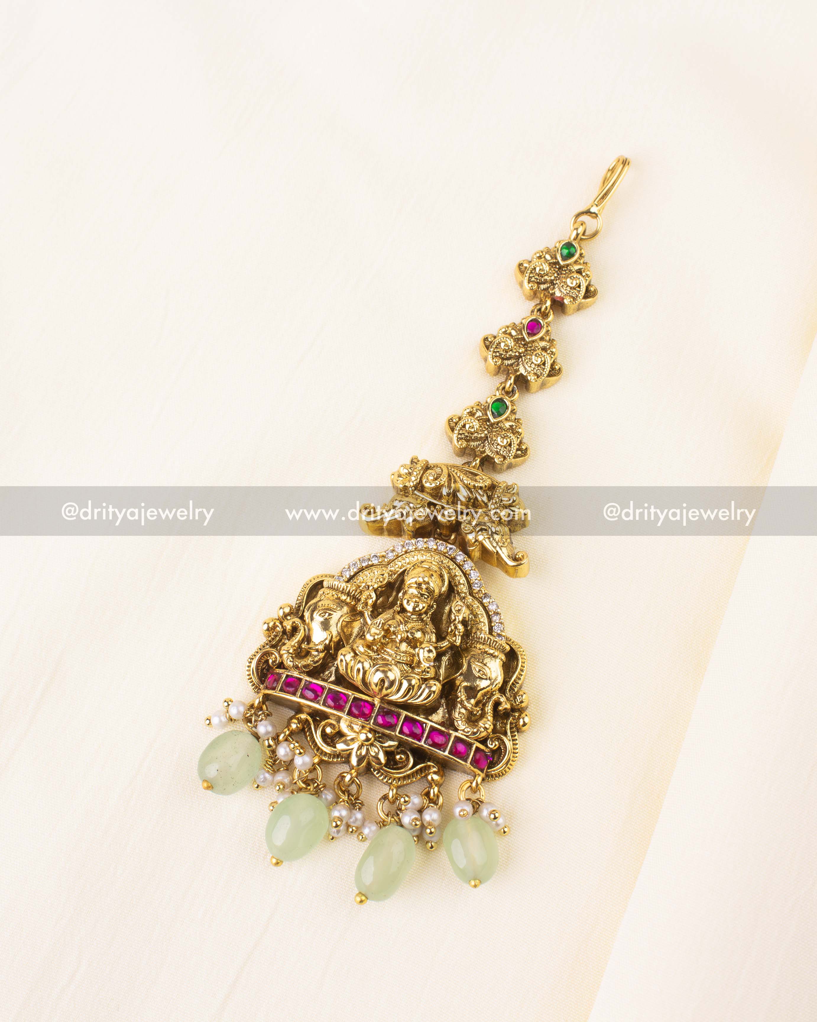 Mint green drop maang tikka with Lakshmi Devi motif and antique gold polish.