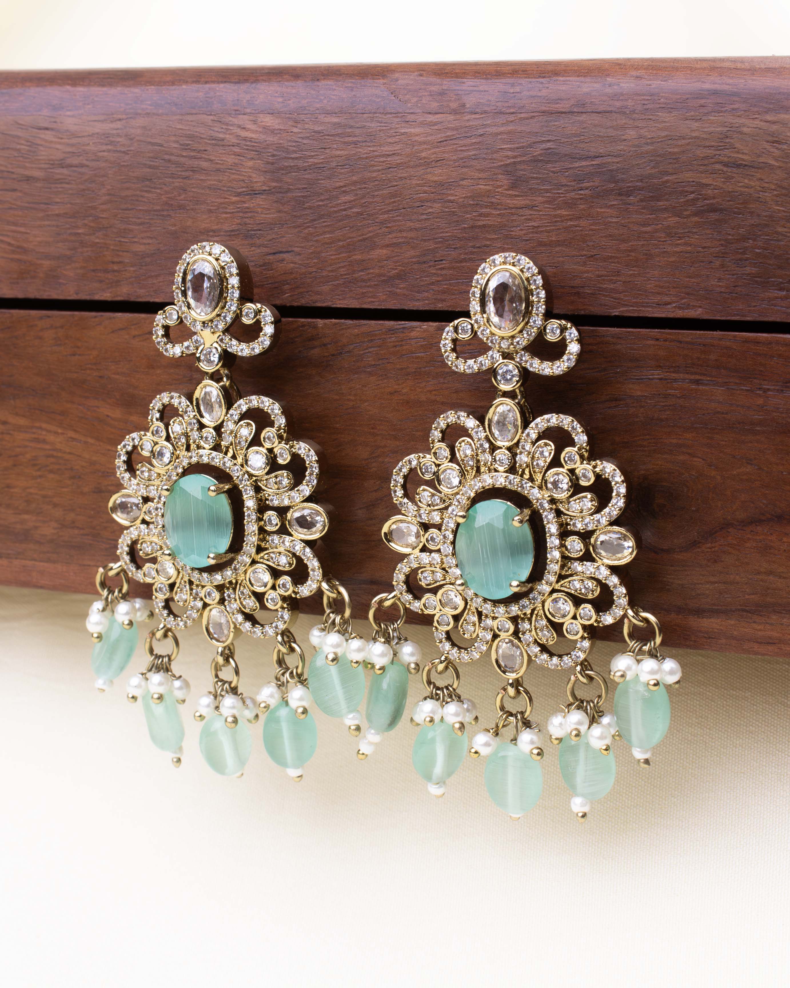 Floral Victorian drop earrings with green gemstone center and pearl bead hangings.