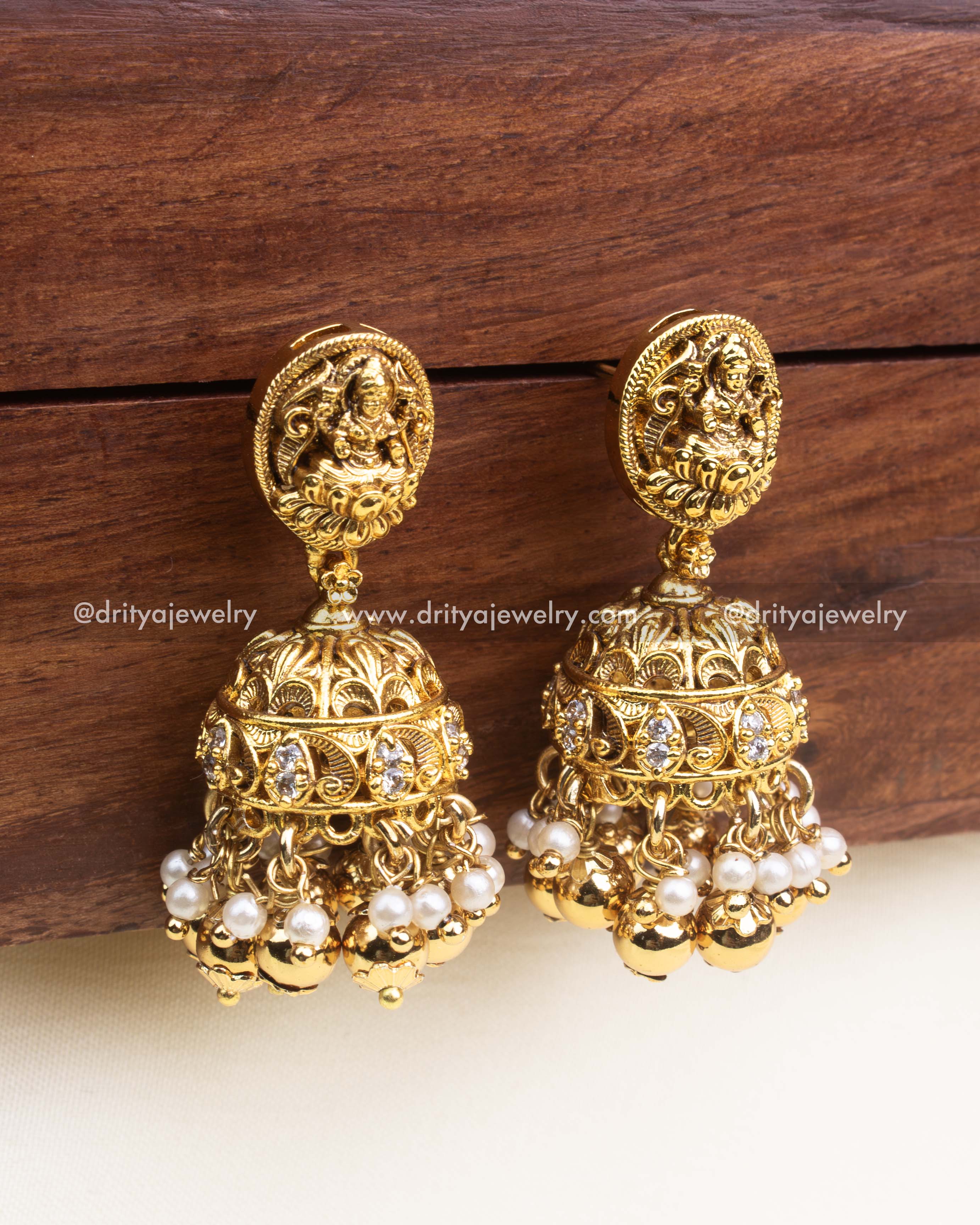 Temple-style gold jhumka earrings with Lakshmi motif, pearl and gold ball drops.