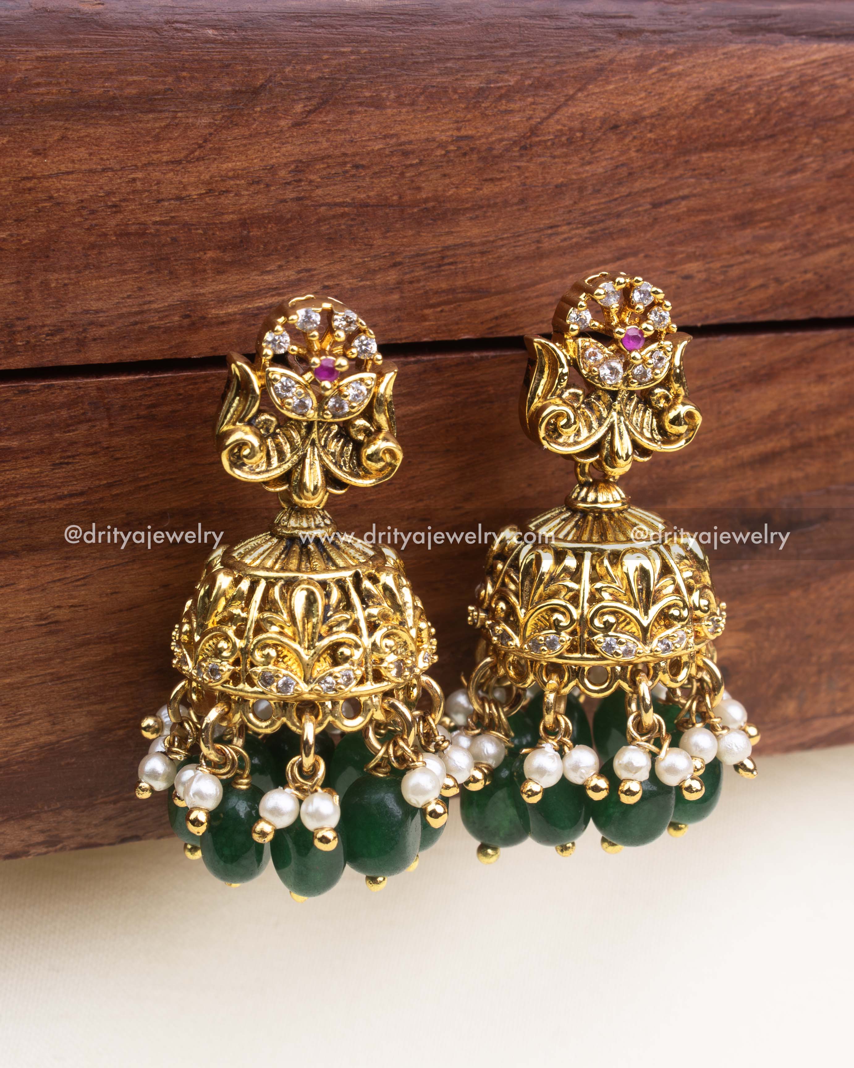 Temple-style jhumka earrings with floral top, antique gold finish, and green bead drops.