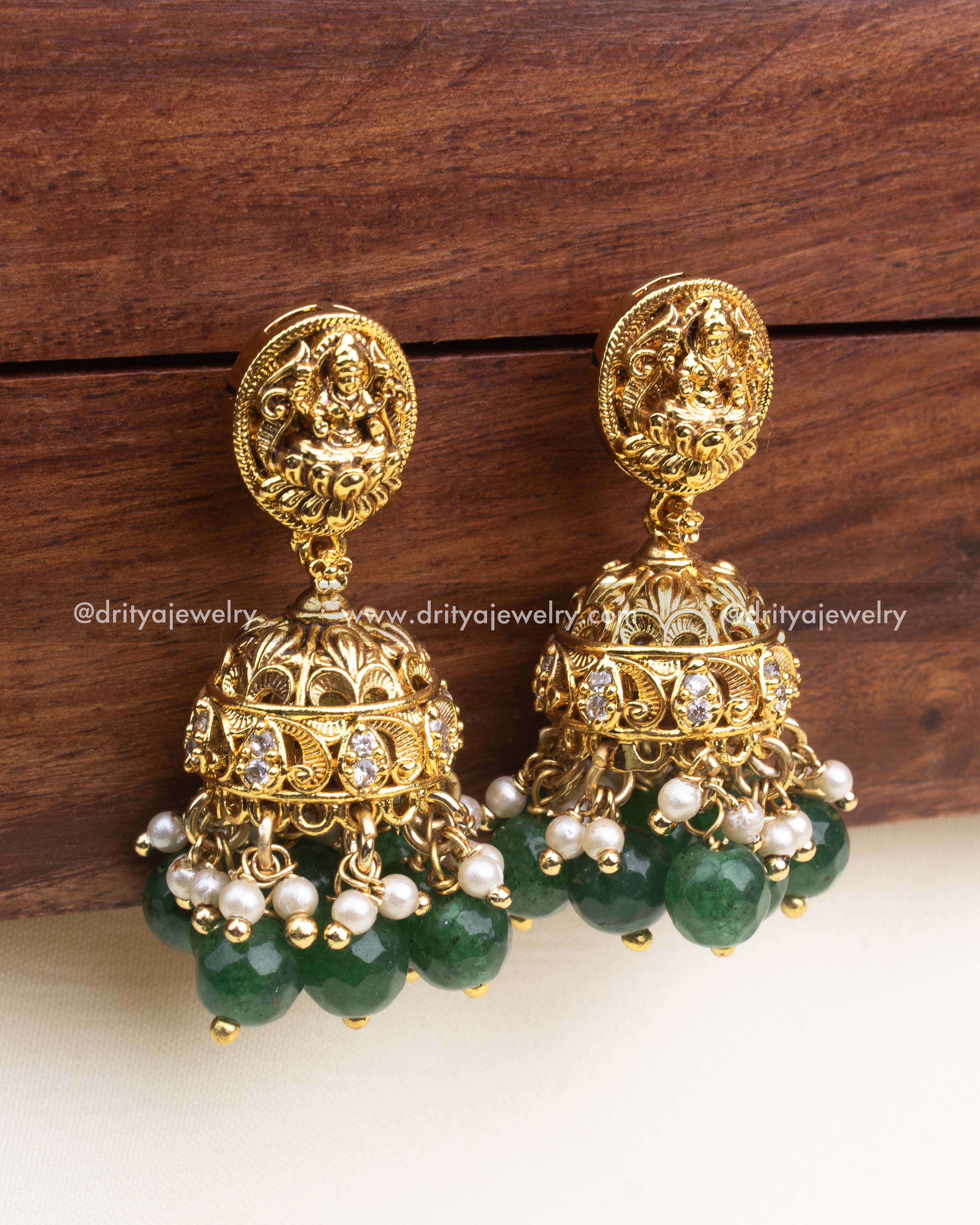 Antique gold temple jhumka earrings with white stones and green bead drops.