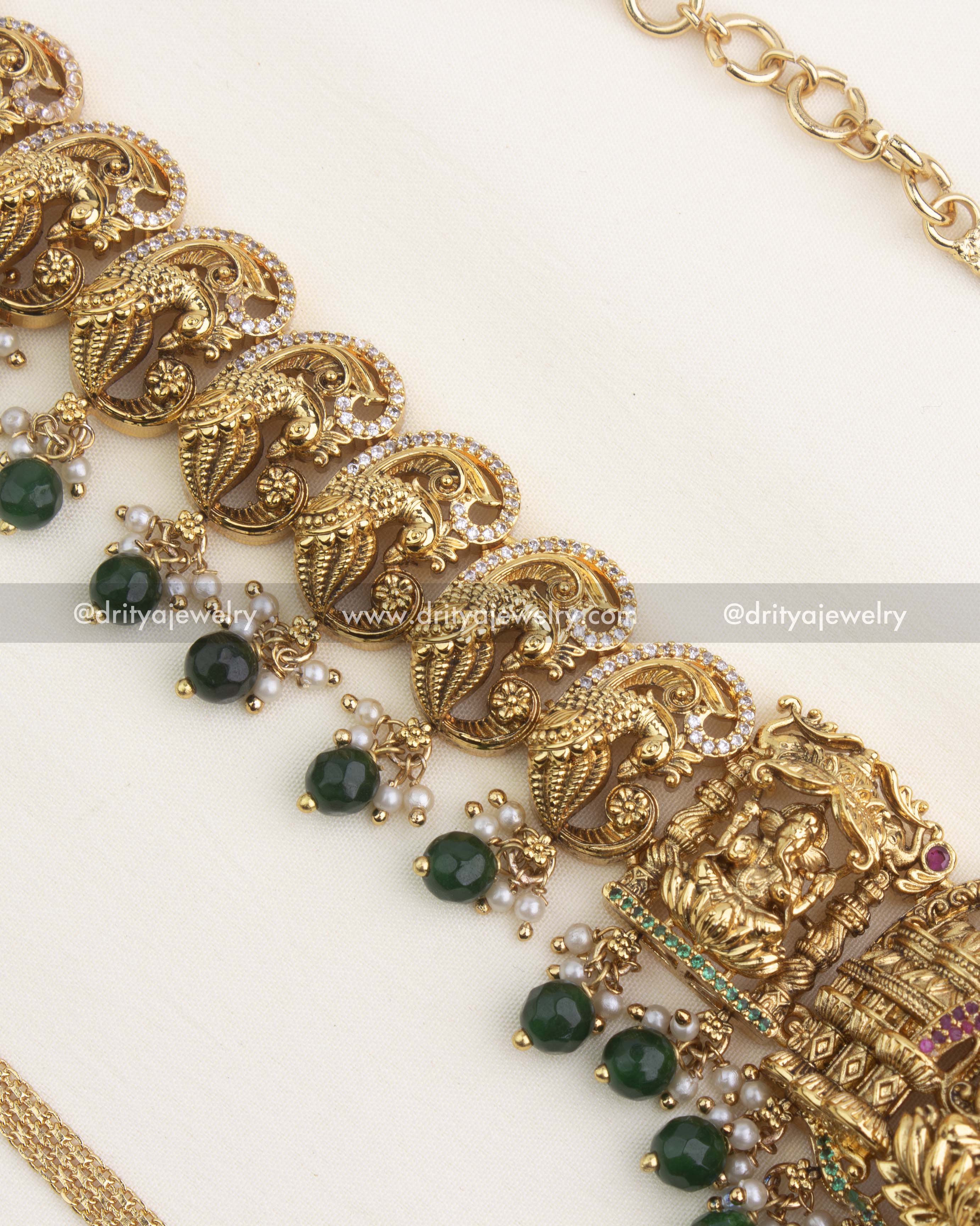 Close-up of intricate peacock nakshi work with pearl clusters and green bead drops.