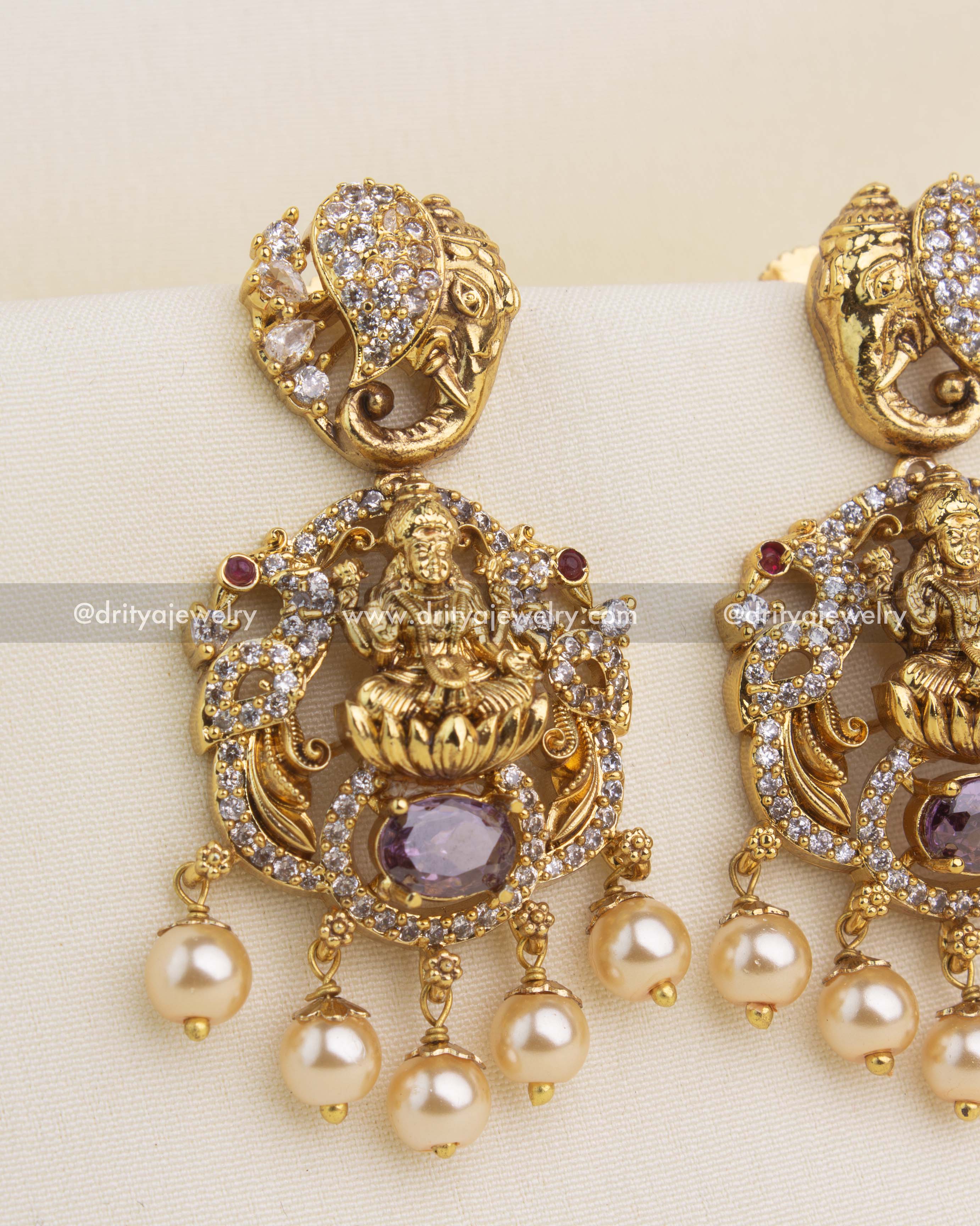 Close-up of temple-style danglers featuring carved Lakshmi, CZ stones, elephant-top stud, and pearl hangings.