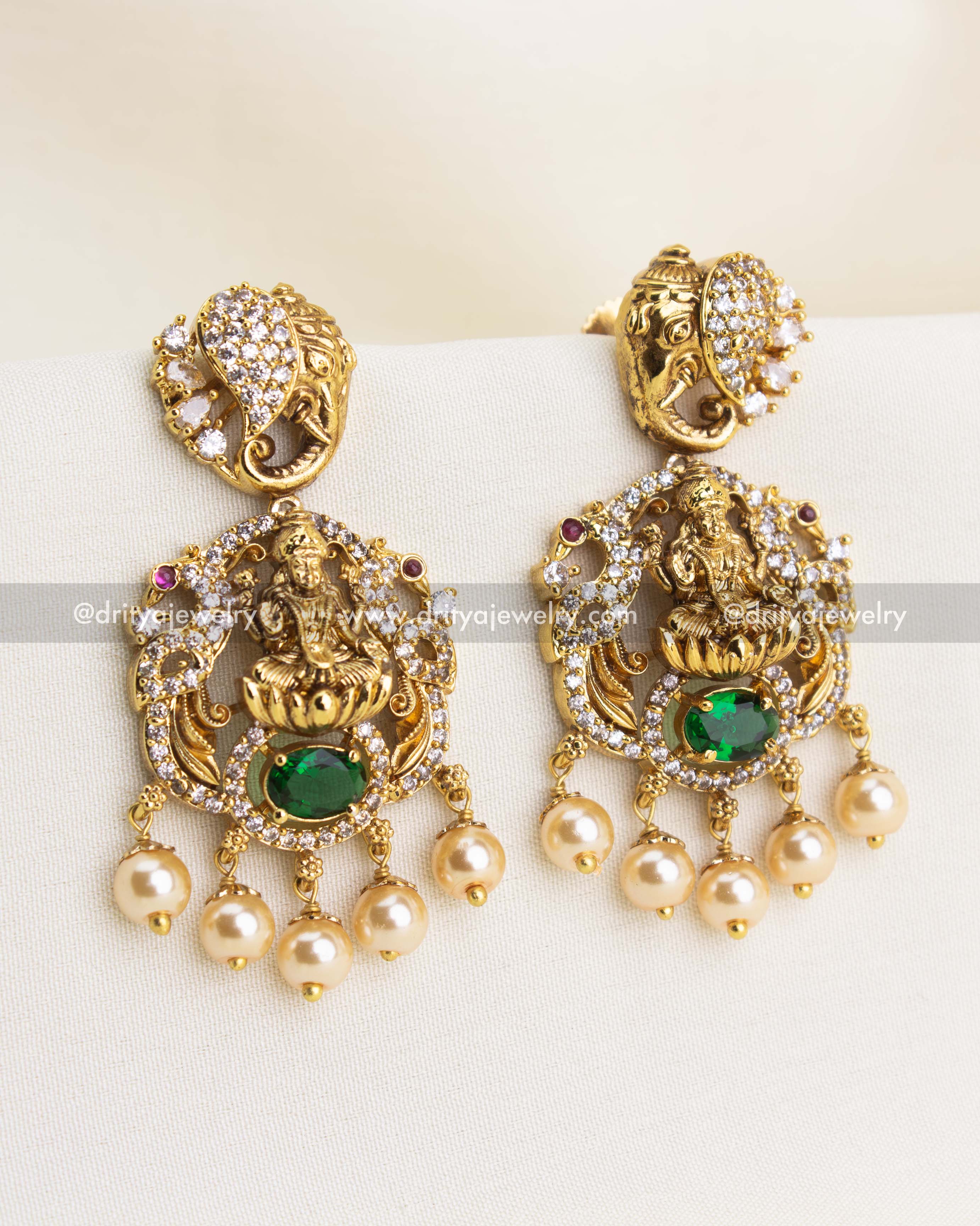 Premium Nakshi temple danglers with Goddess Lakshmi, green oval stone, CZ accents, and pearl drops.