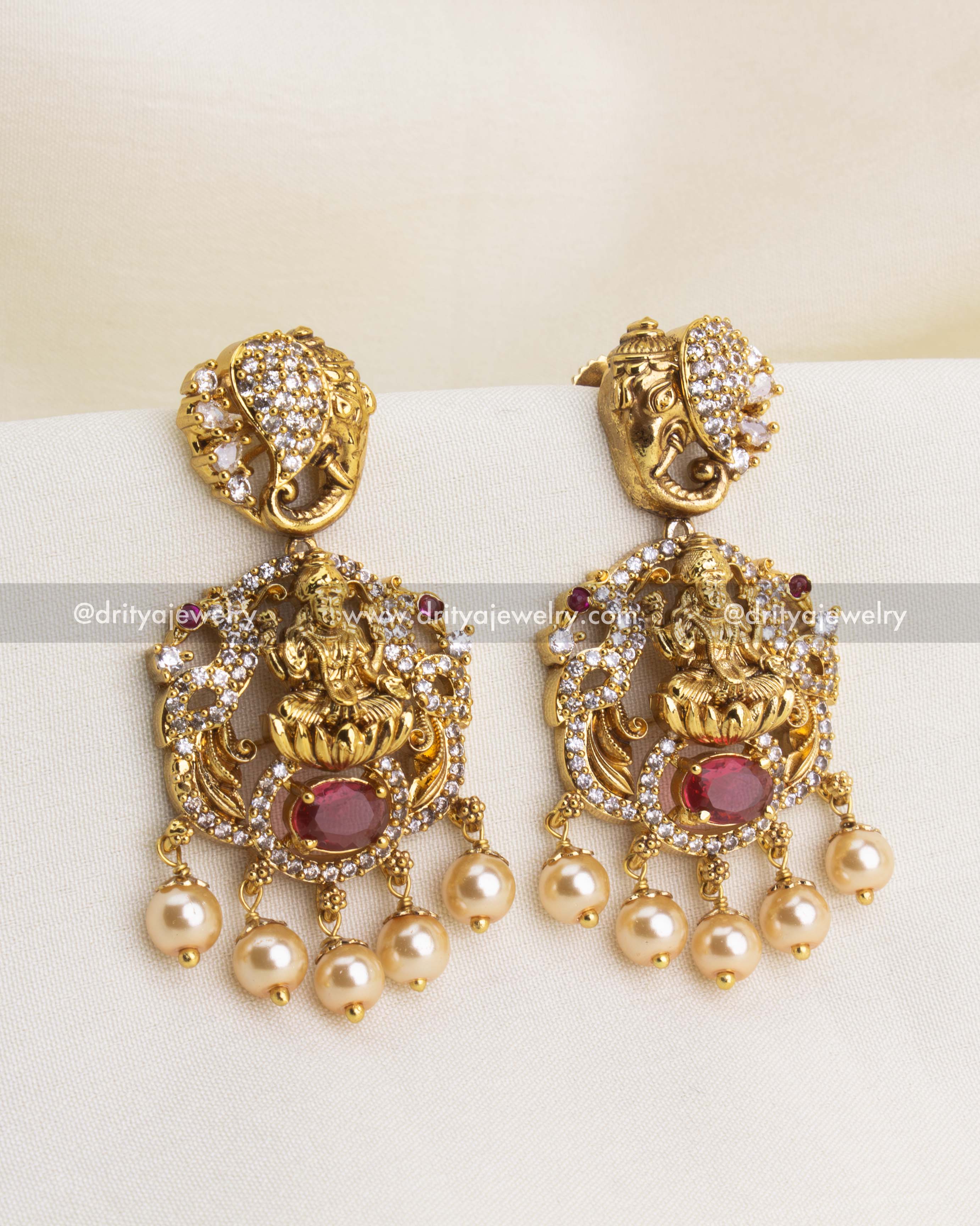 Premium Nakshi temple danglers with Goddess Lakshmi, red oval stone, CZ accents, and pearl drops.