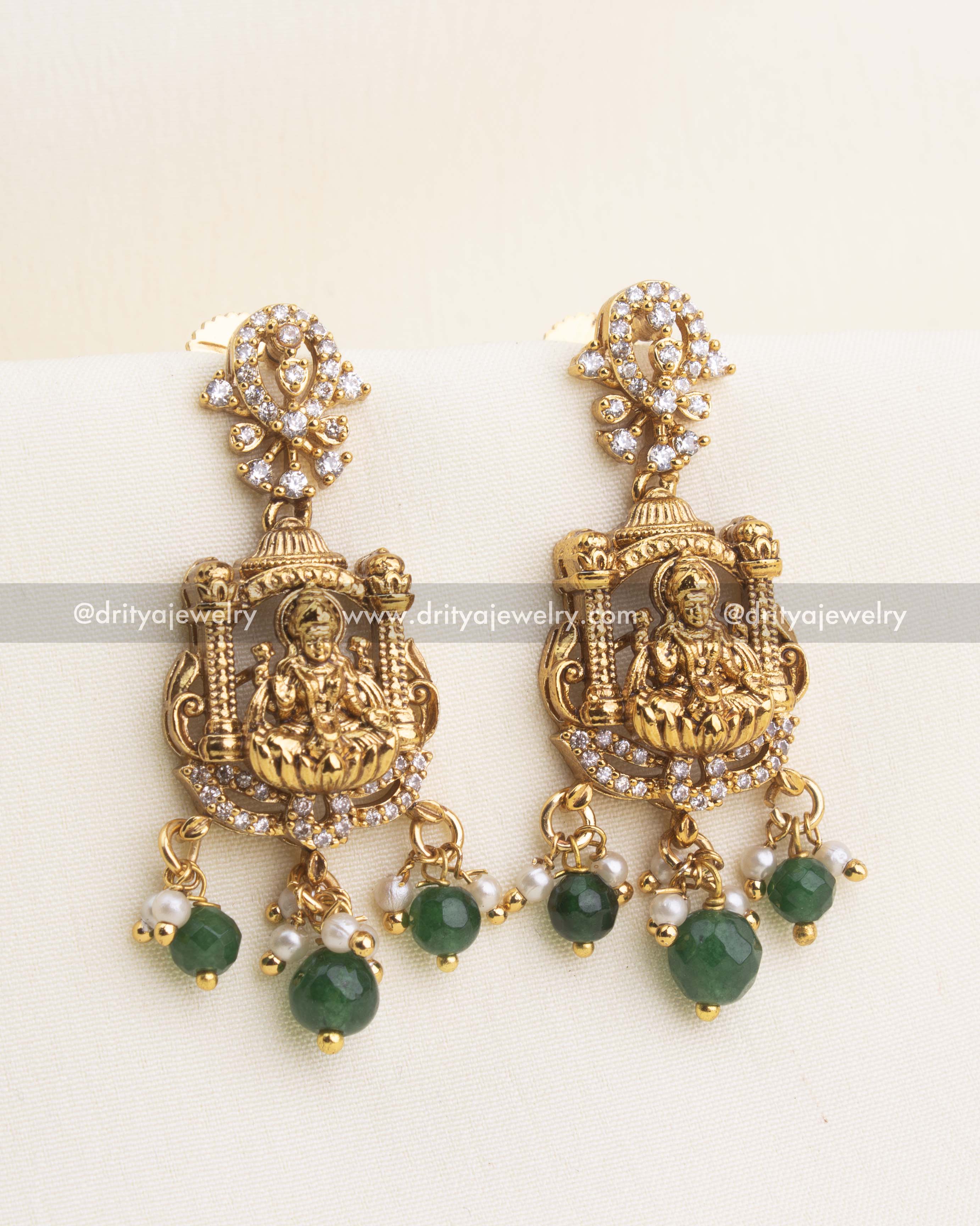 Intricate Nakshi temple earrings with Lakshmi motif, cz stones, pearls, and green bead hangings.
