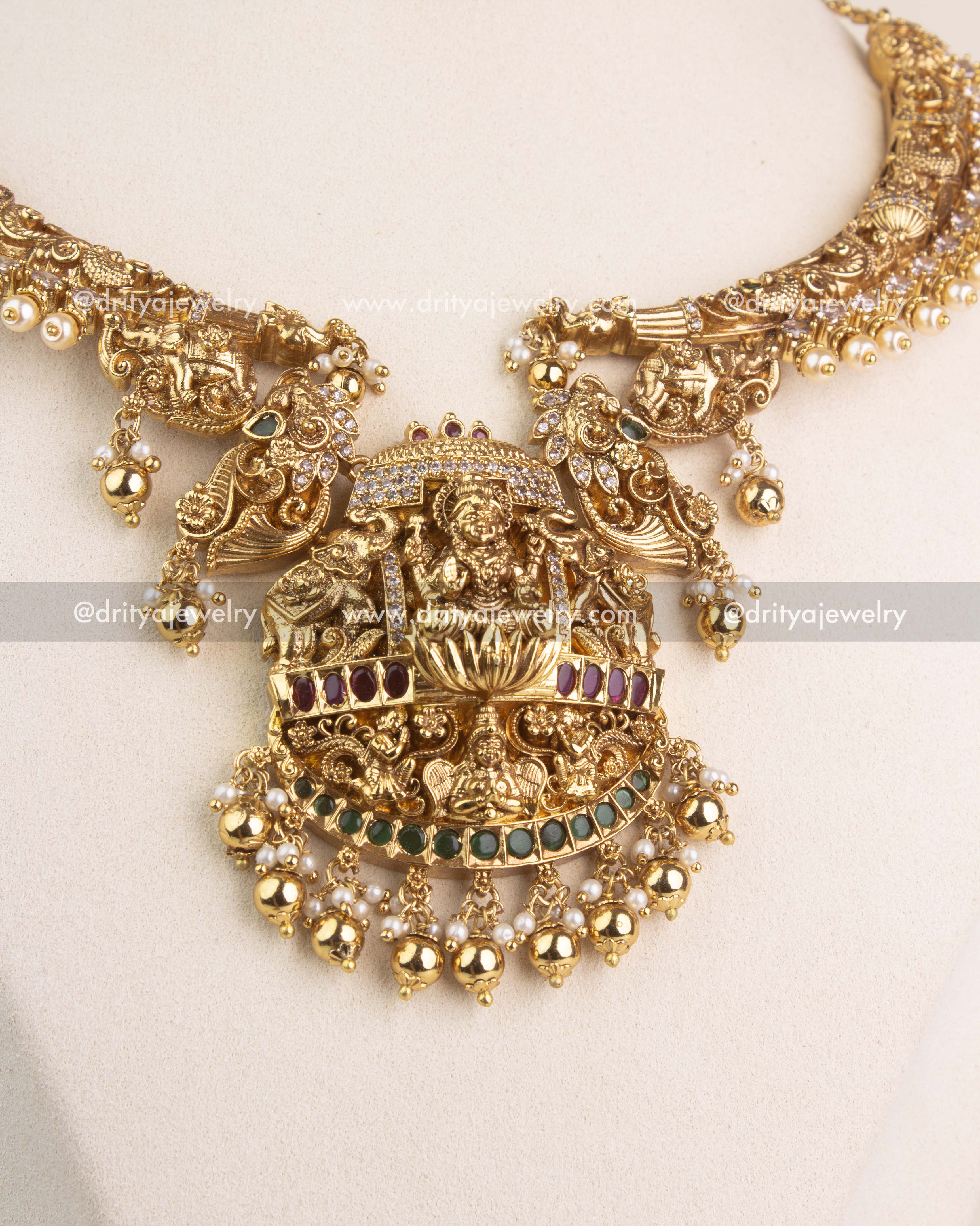 Detailed view of Lakshmi Devi pendant with ruby-green stone setting, pearl fringe, and peacock motifs.