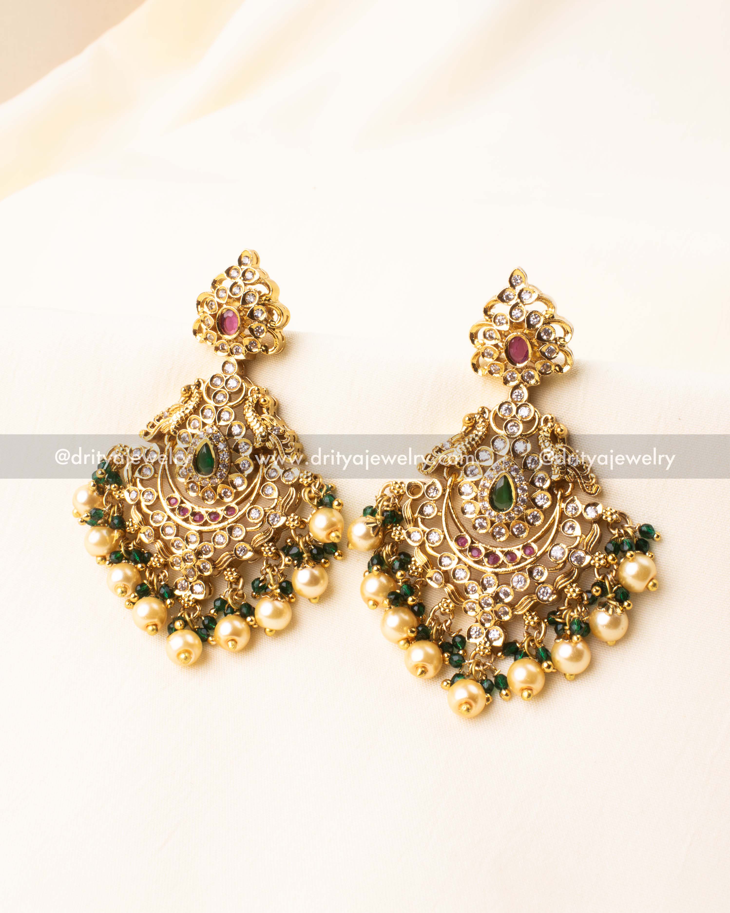 Traditional gold dangler earrings with emerald center, CZ stones, pearl and green bead clusters.
