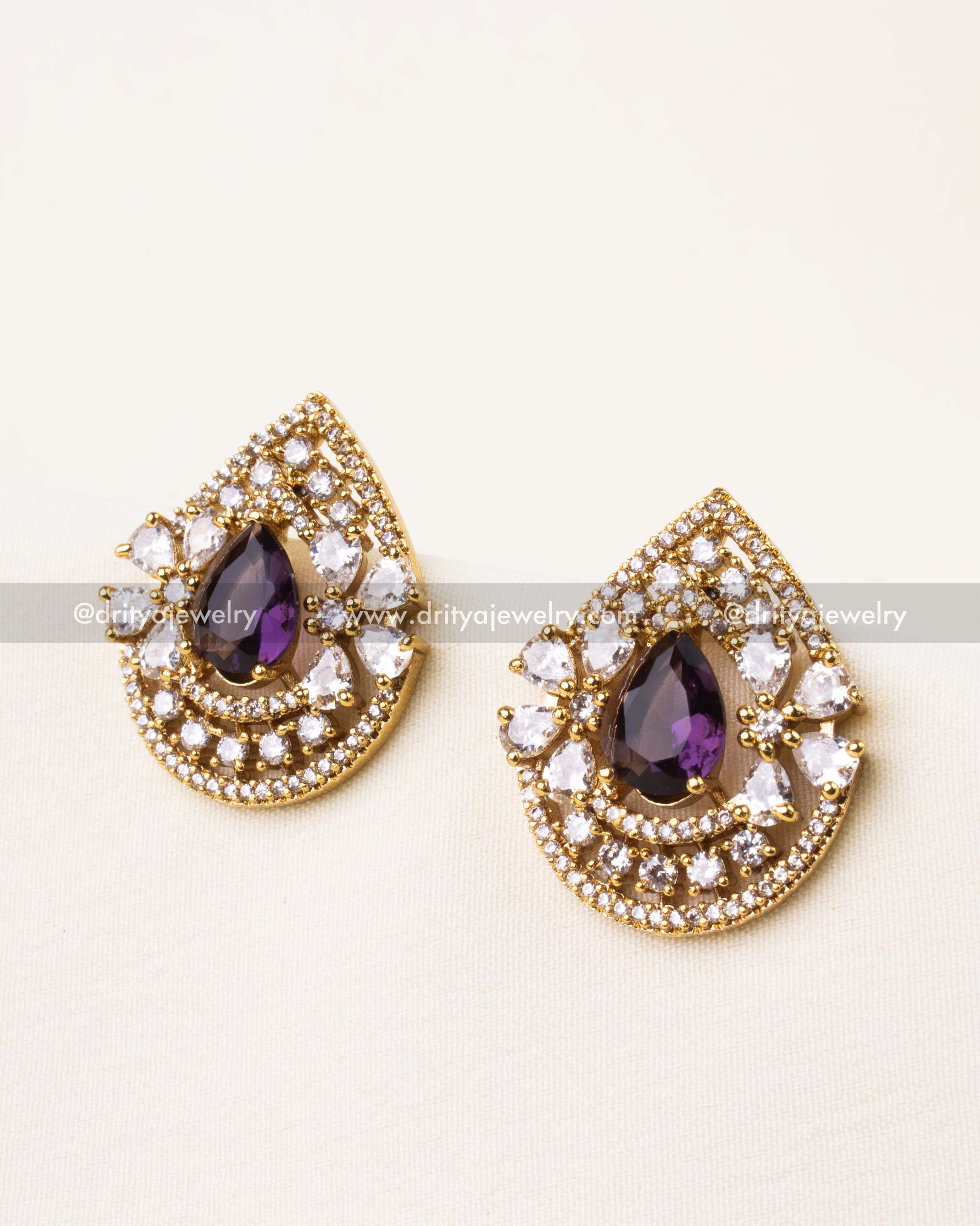 Teardrop purple CZ stud earrings with concentric CZ halo in gold finish.