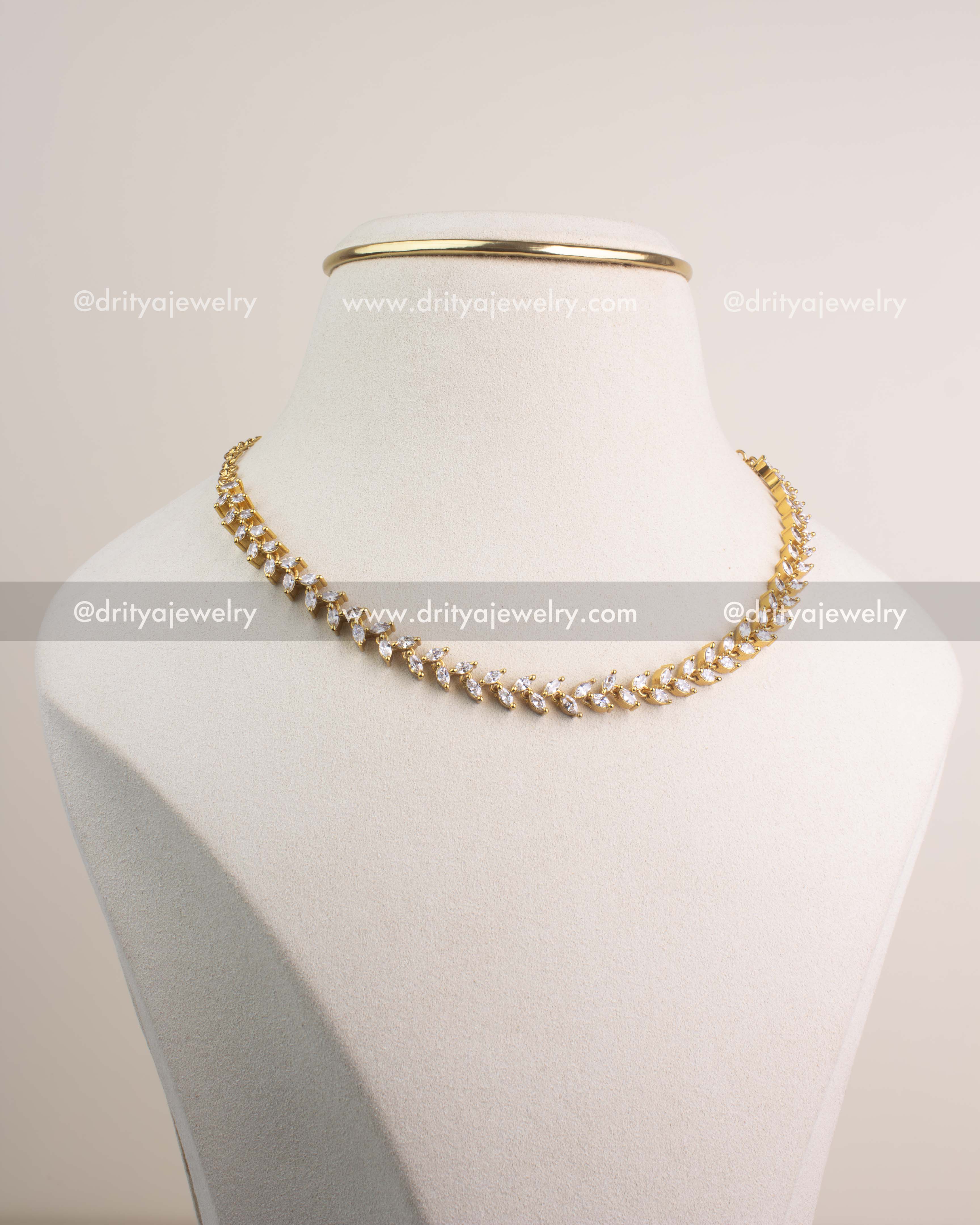 Close-up of gold necklace with diamond-alike marquise CZ stones in vine pattern.