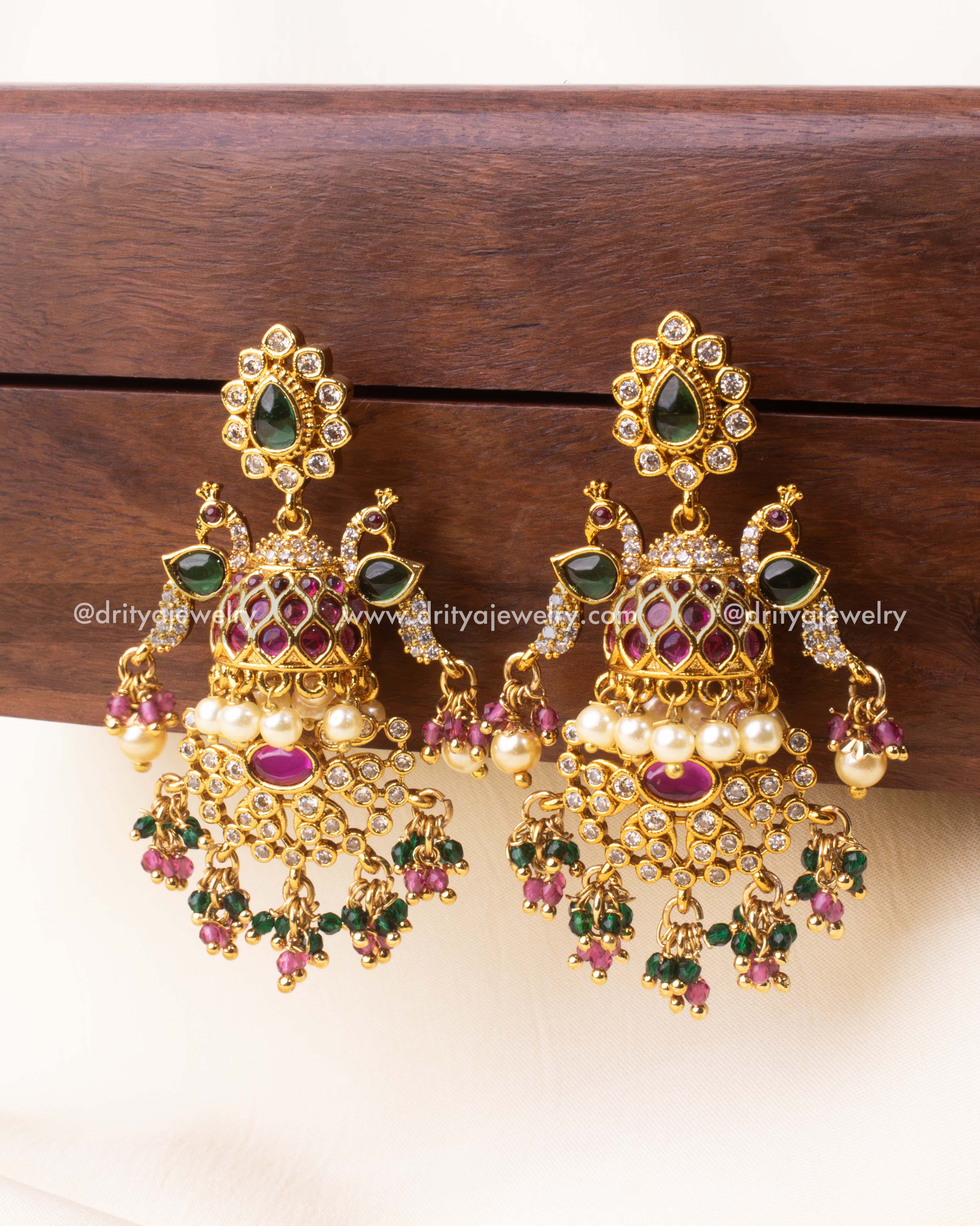 Opulent Jhumka earrings featuring peacock motifs, kundan stones, pearls, and multicolor beads.