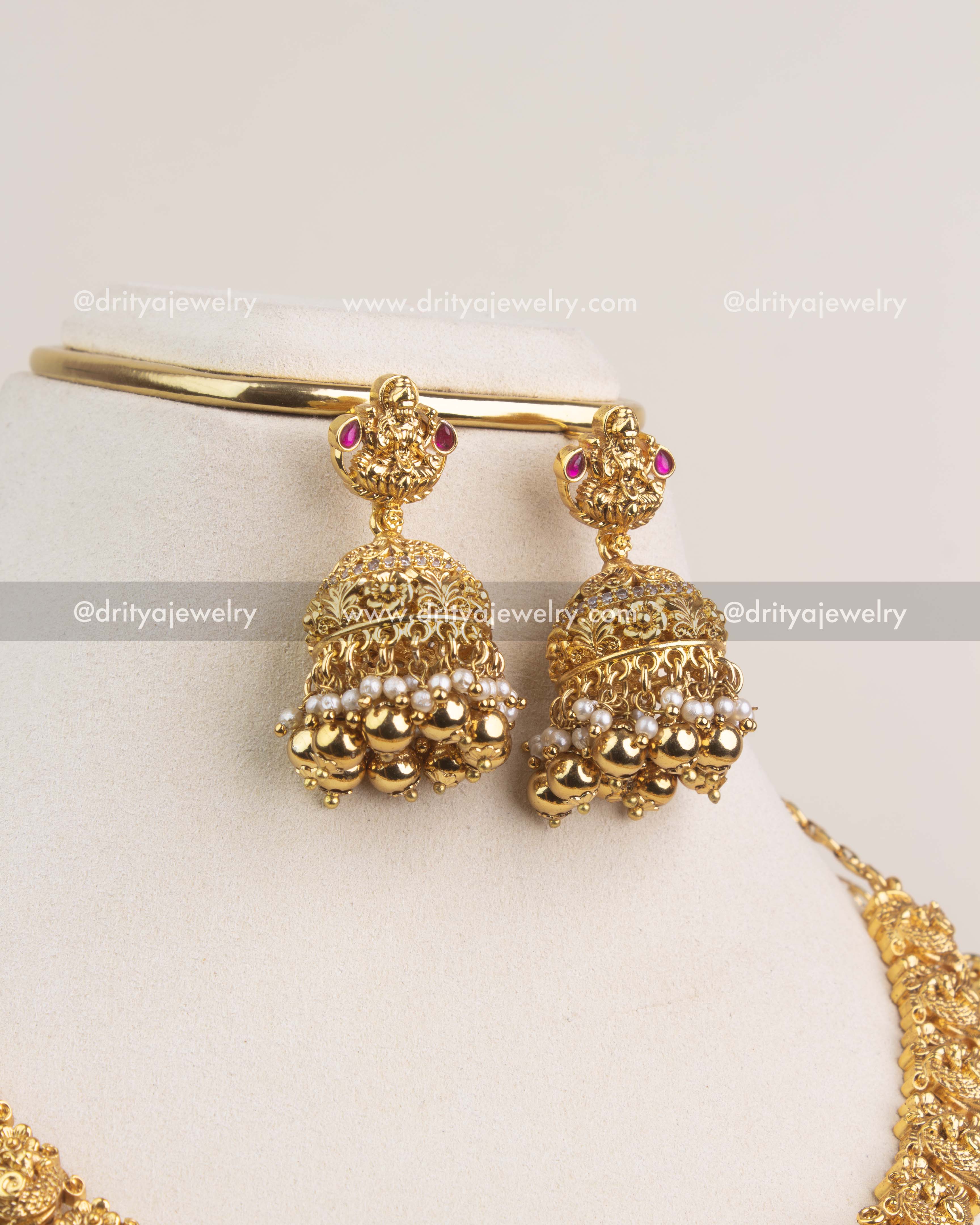 Matching temple jhumkas with ruby stones, gold beads, and pearl detailing.