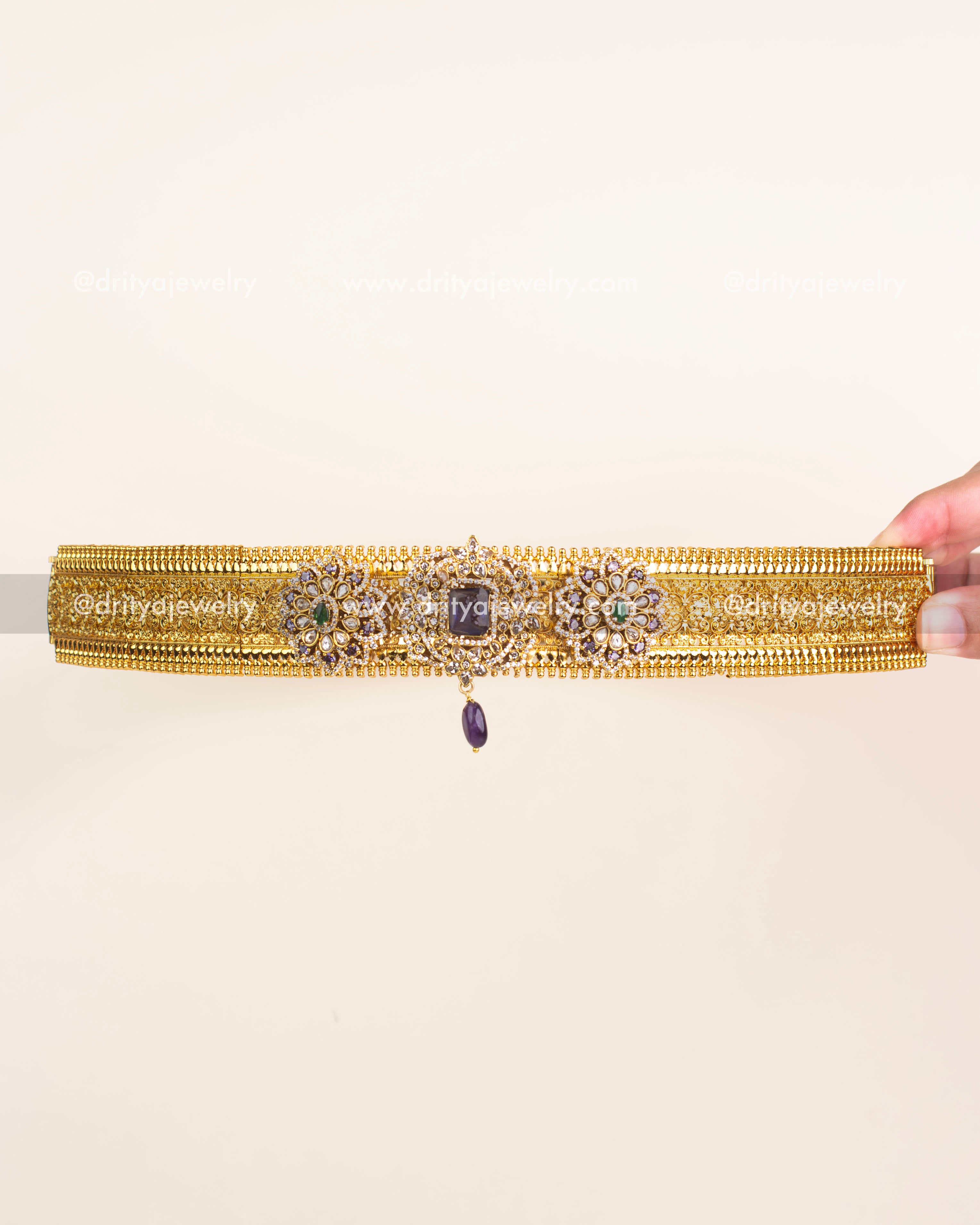 Antique gold waist belt with floral kundan work and central violet gemstone.