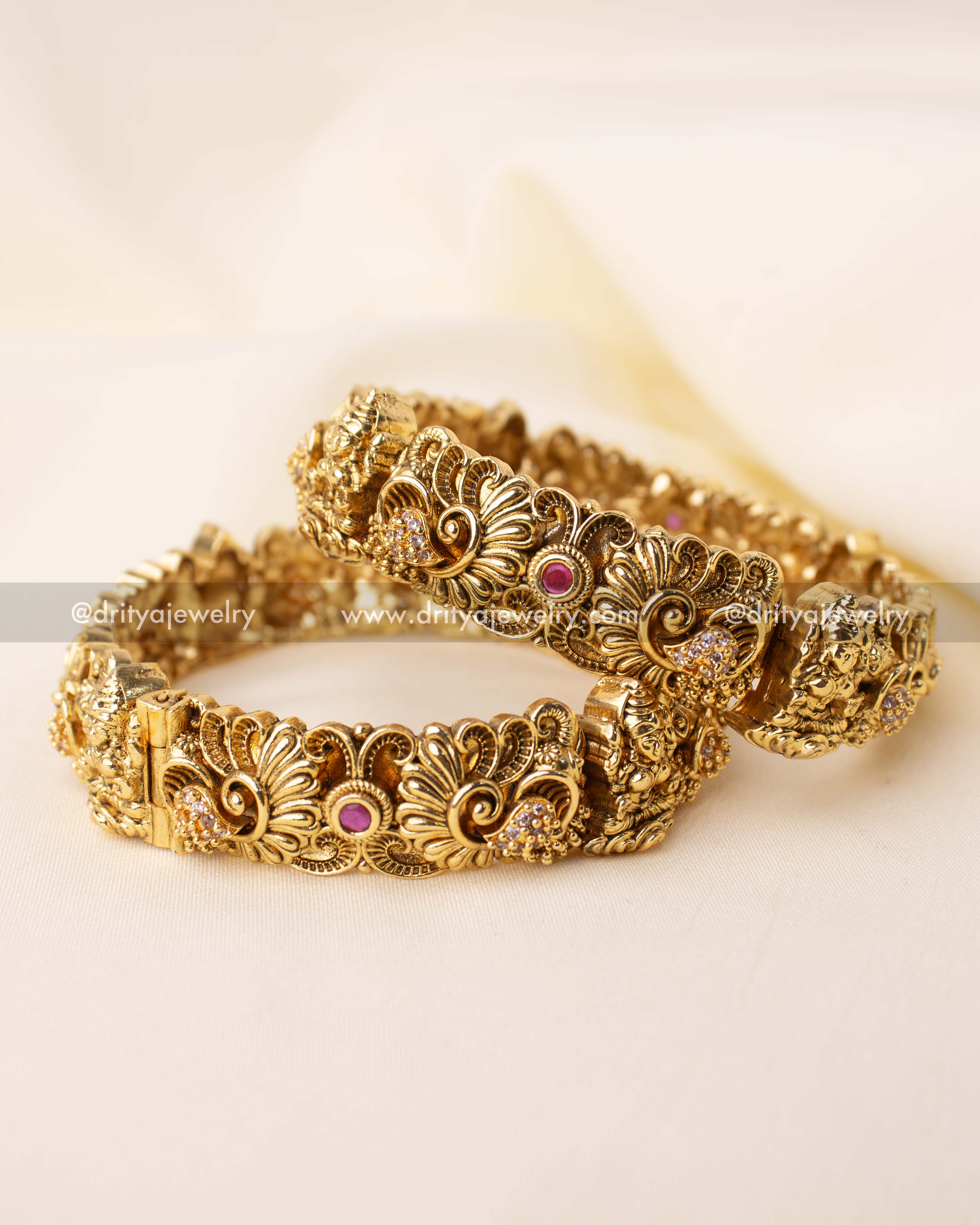 Pair of intricately carved Nakshi bangles with pink stones and antique gold finish.