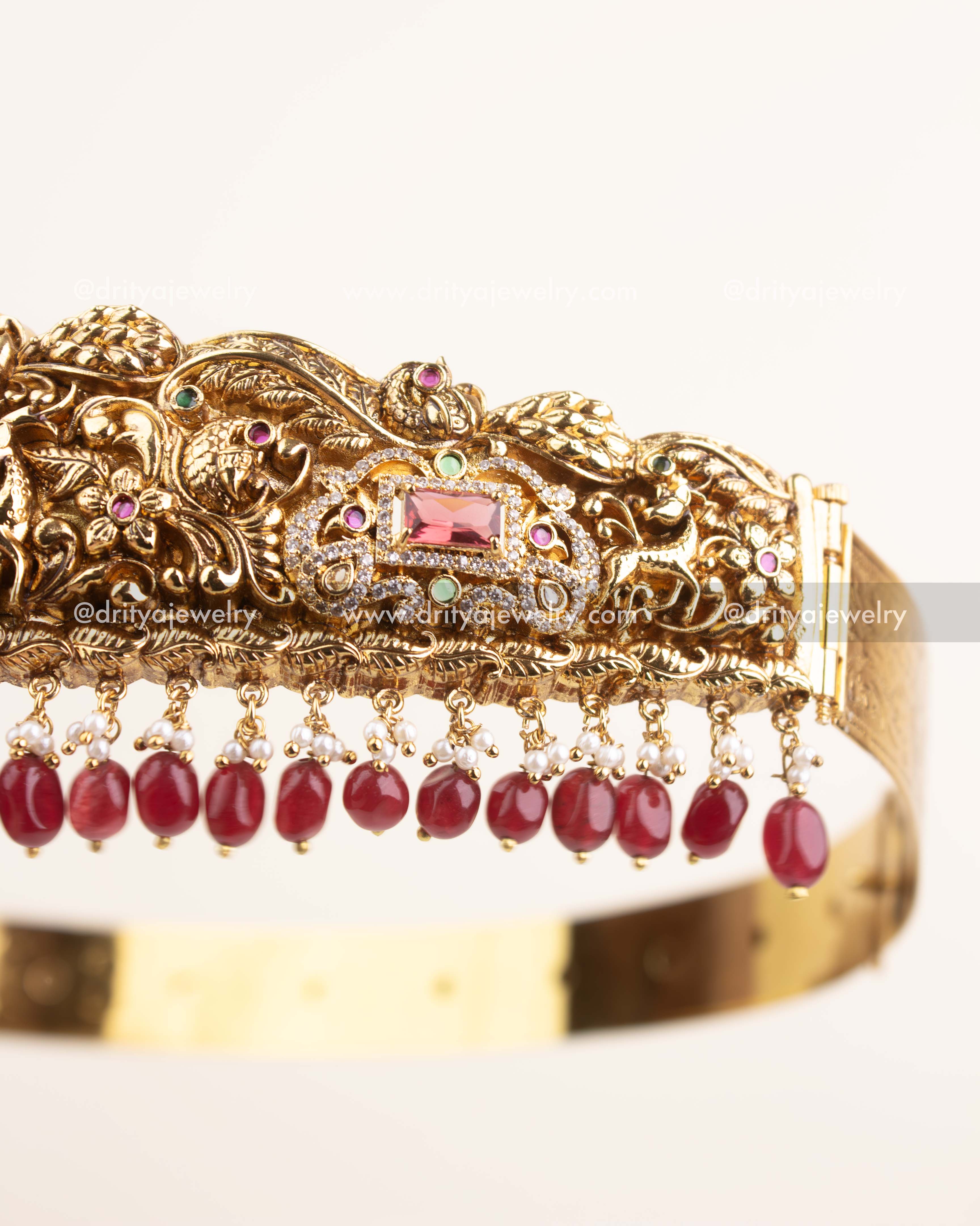 Side view of antique gold temple vadanam showing ruby and pearl hanging embellishments.