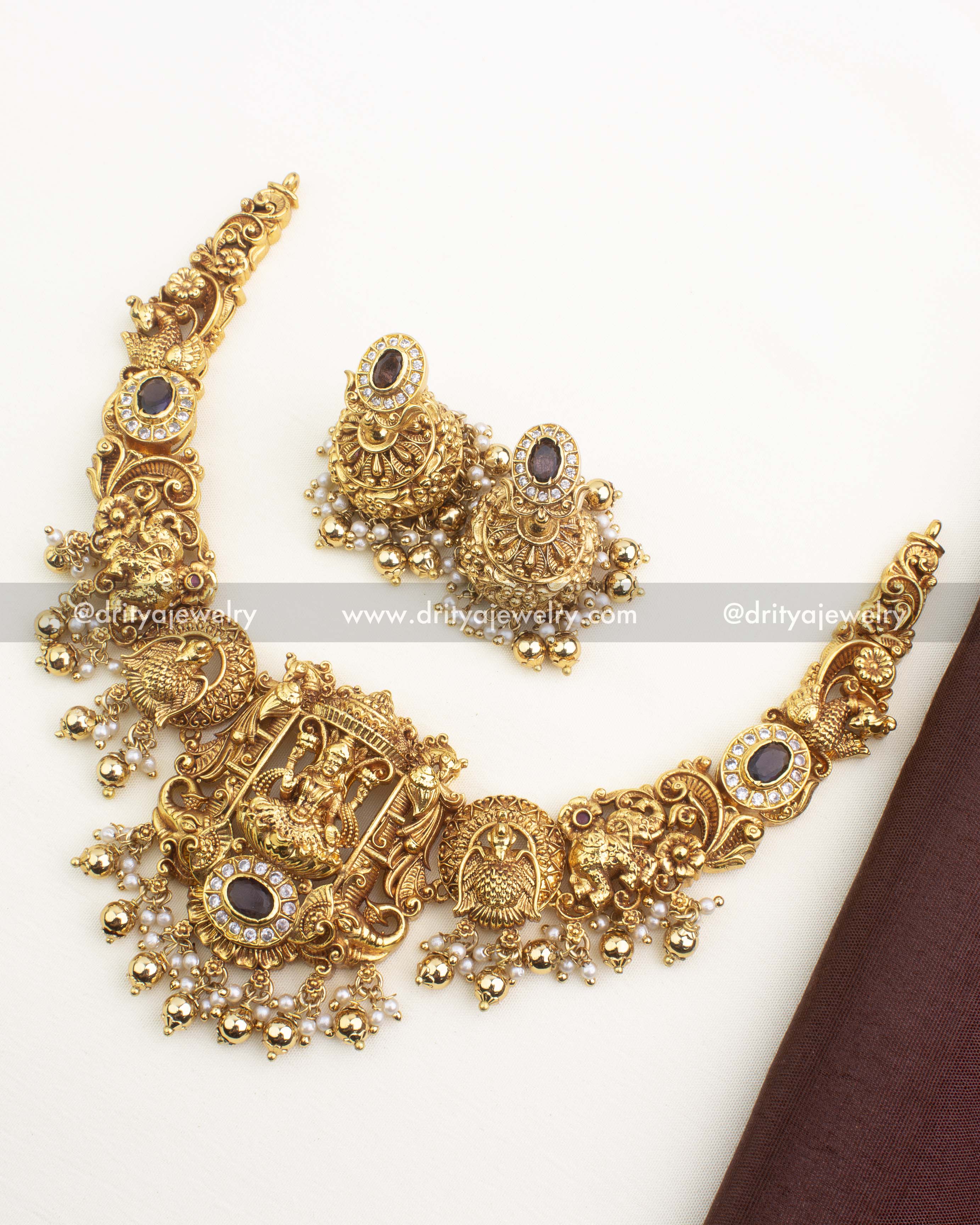 Antique gold nakshi short necklace set featuring goddess motif, peacock carvings, CZ stone accents, pearl drops, and matching jhumkas.