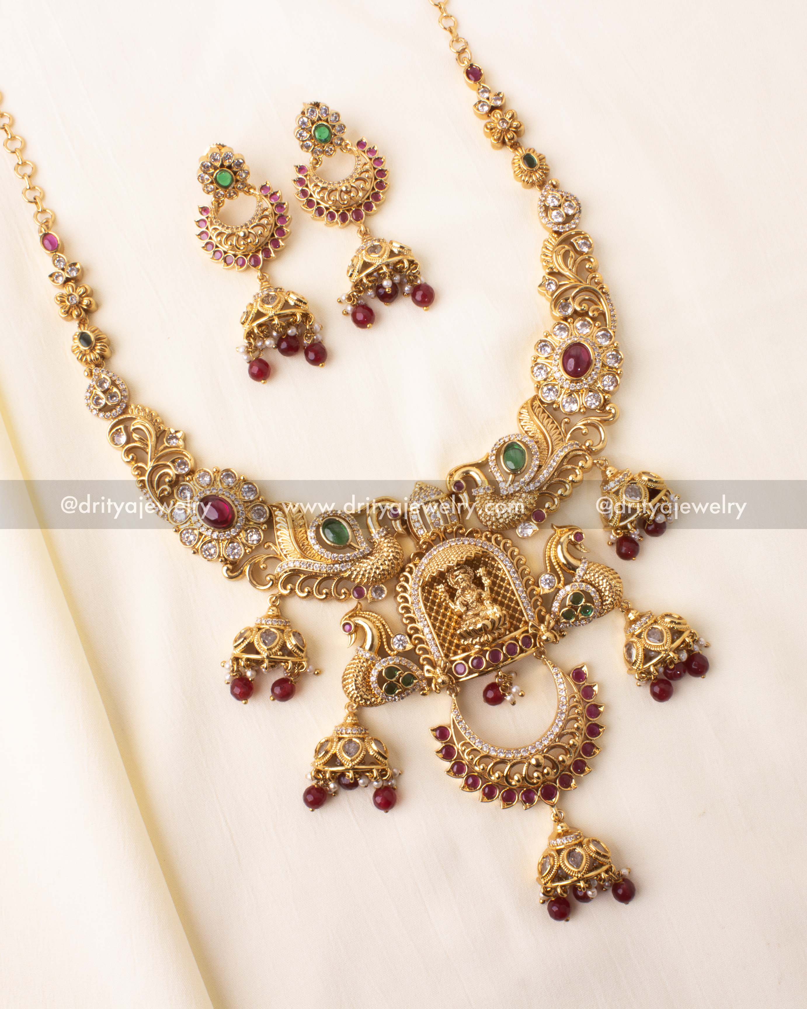 Antique gold short necklace with goddess and peacock design, paired with matching earrings and ruby drop details.