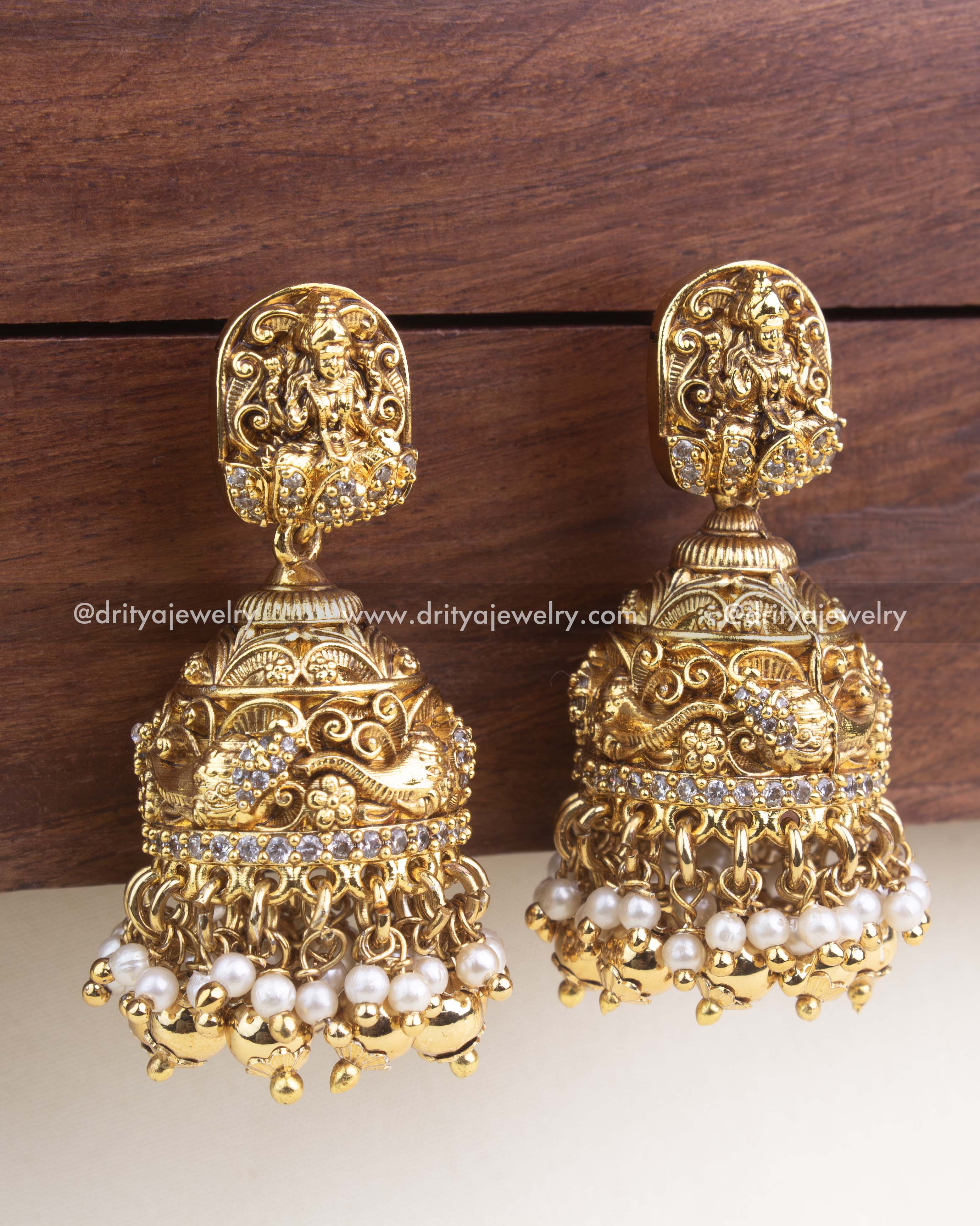 Antique gold temple jhumkas featuring goddess motif studs, nakshi dome work, and pearl cluster drops