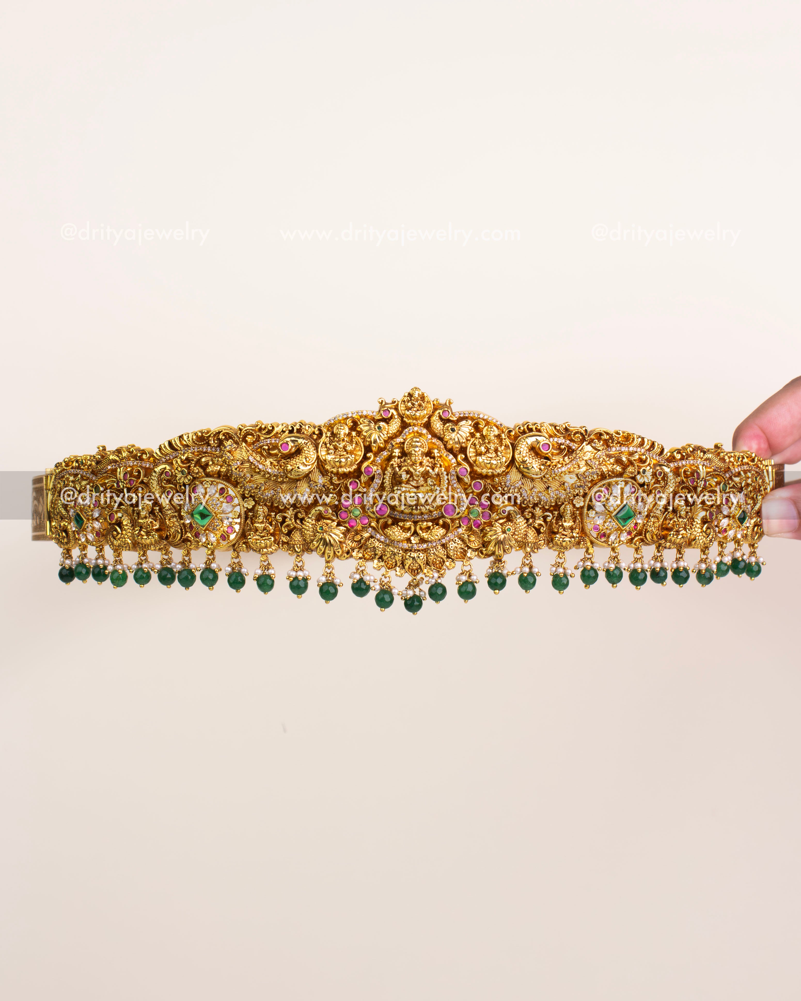 Antique gold temple vadanam with Goddess Lakshmi motif, ruby-emerald accents, and emerald bead hangings.