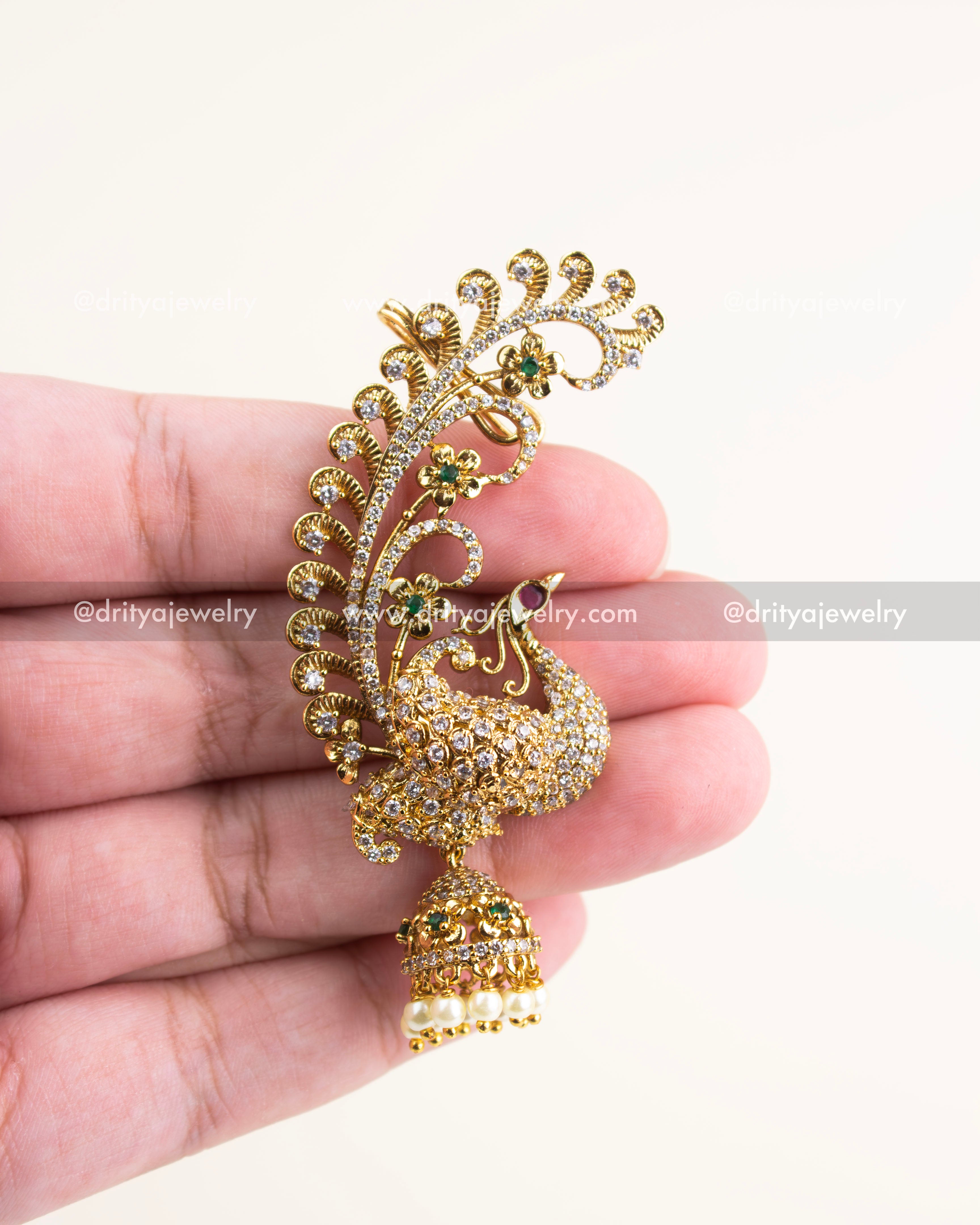 Close-up of peacock motif ear cuffs with intricate floral curls and white CZ stone detailing.