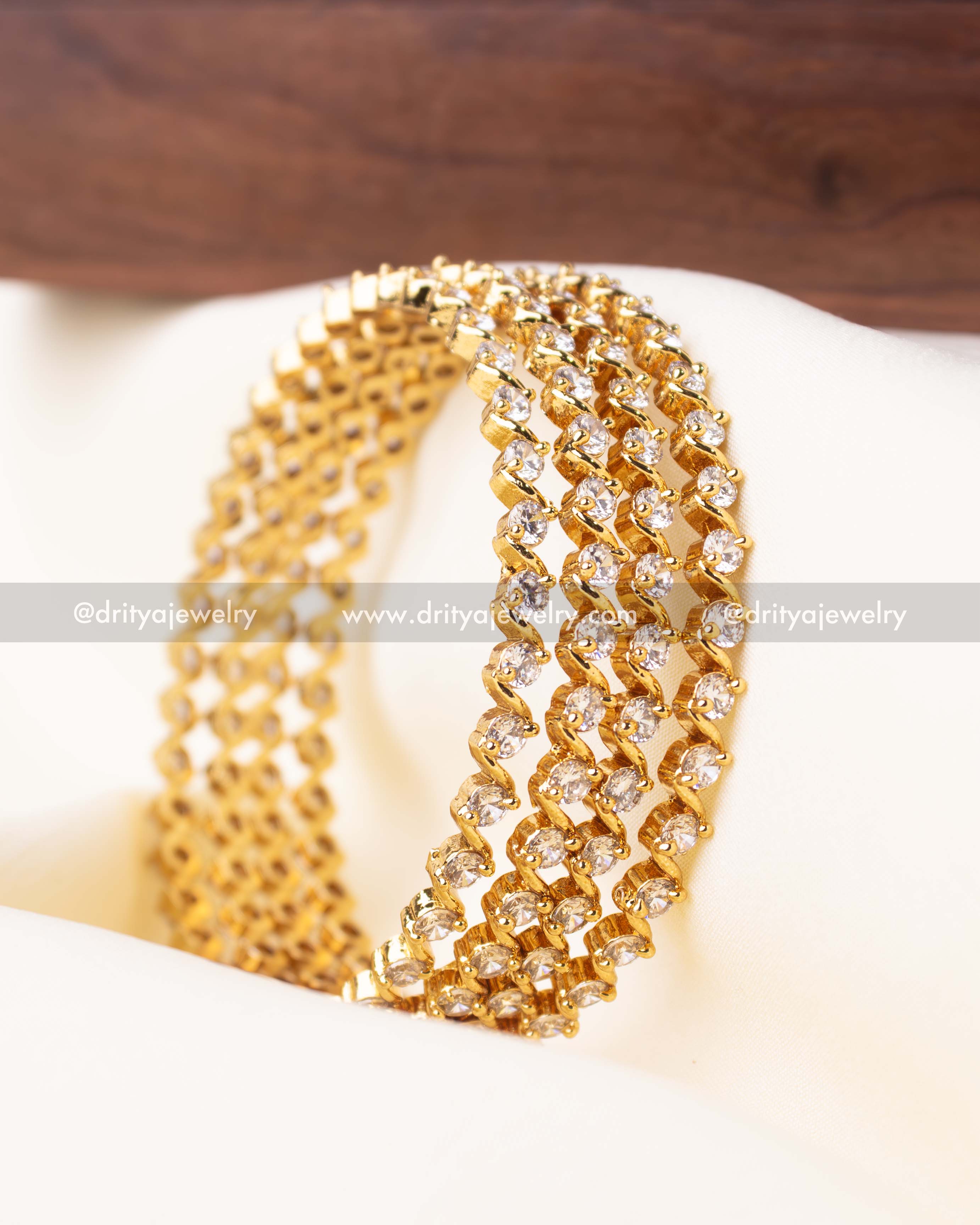 Set of 4 gold-plated bangles featuring solitaire-style white stones in a zig-zag pattern