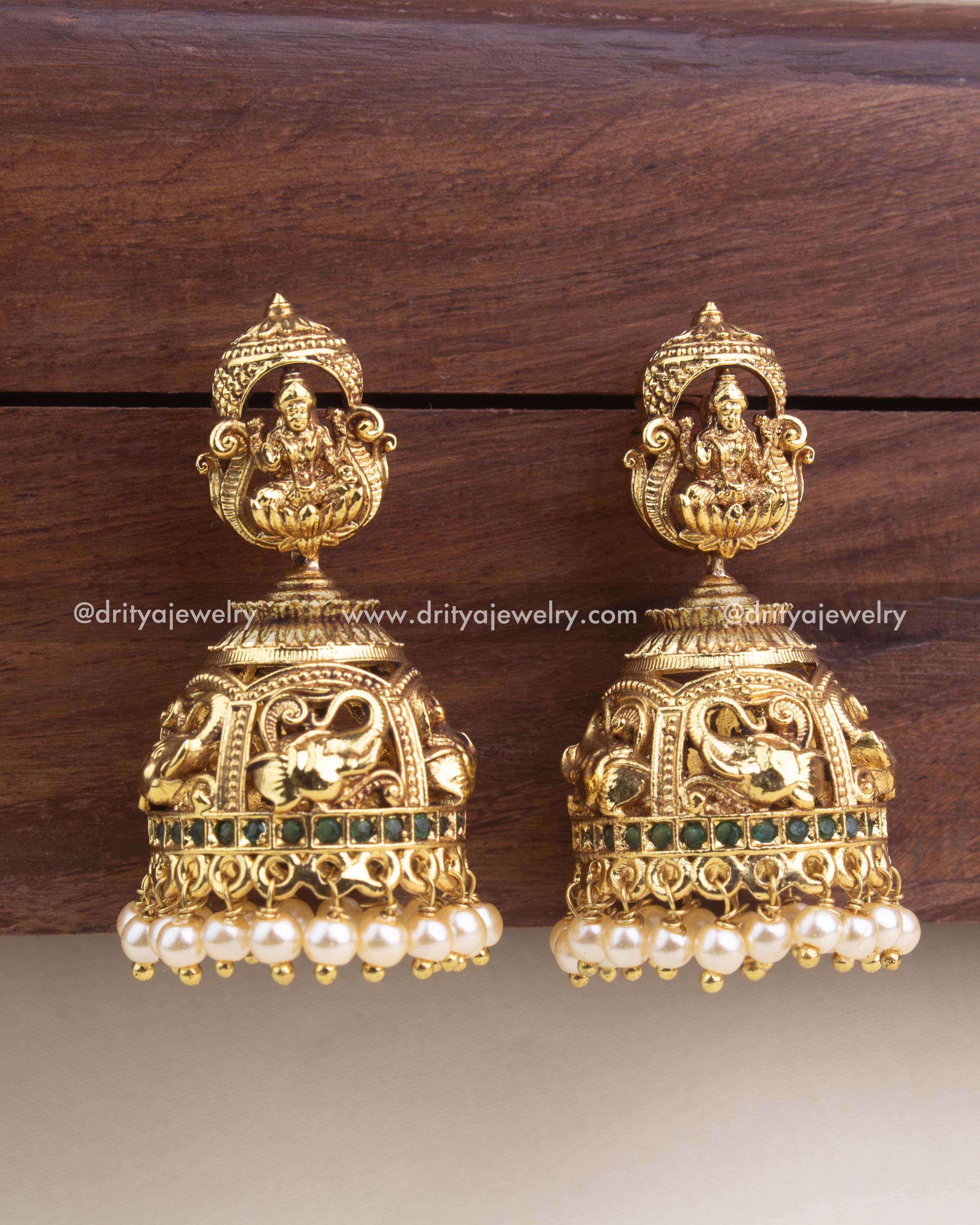 Antique gold temple jhumkas with Lakshmi motif, green stone detailing, and pearl drops from Dritya Jewelry.