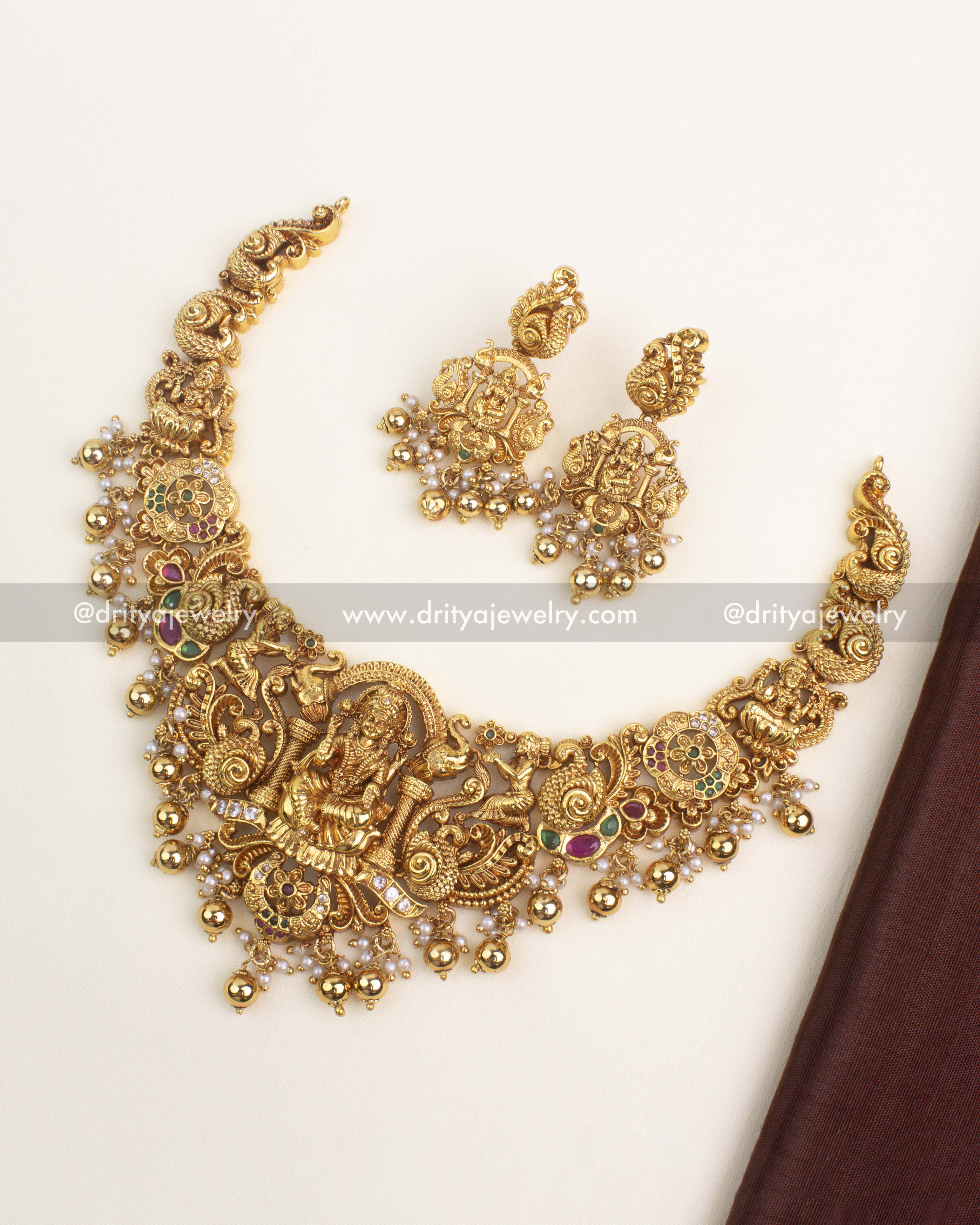 Gold-plated temple short necklace with Lakshmi pendant, ruby and emerald stones, and Nakshi detailing.