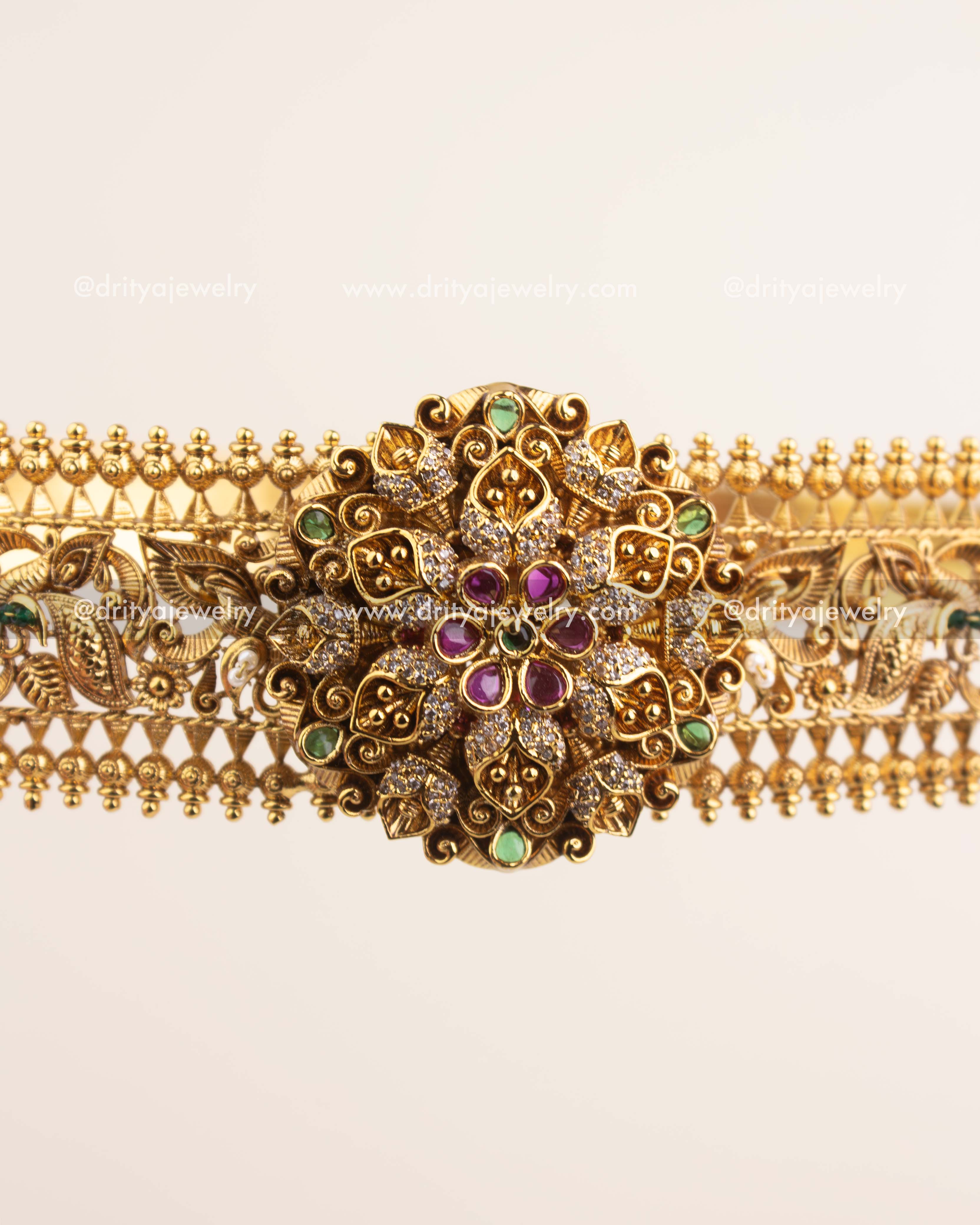 Handcrafted floral centerpiece of vadanam featuring ruby and emerald stones in antique gold finish.