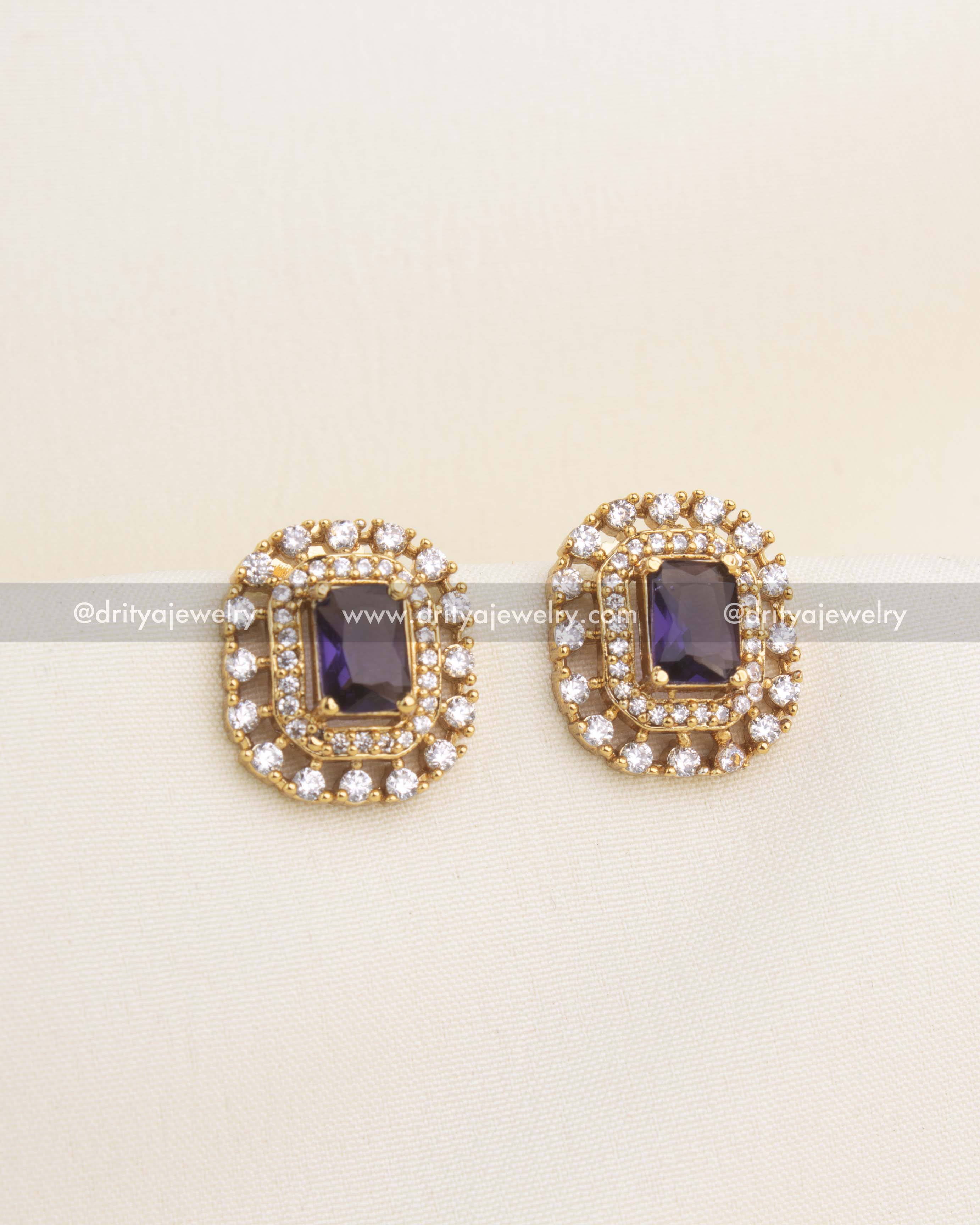 Gold-plated CZ stud earrings with deep purple center stone and layered CZ diamond halos.