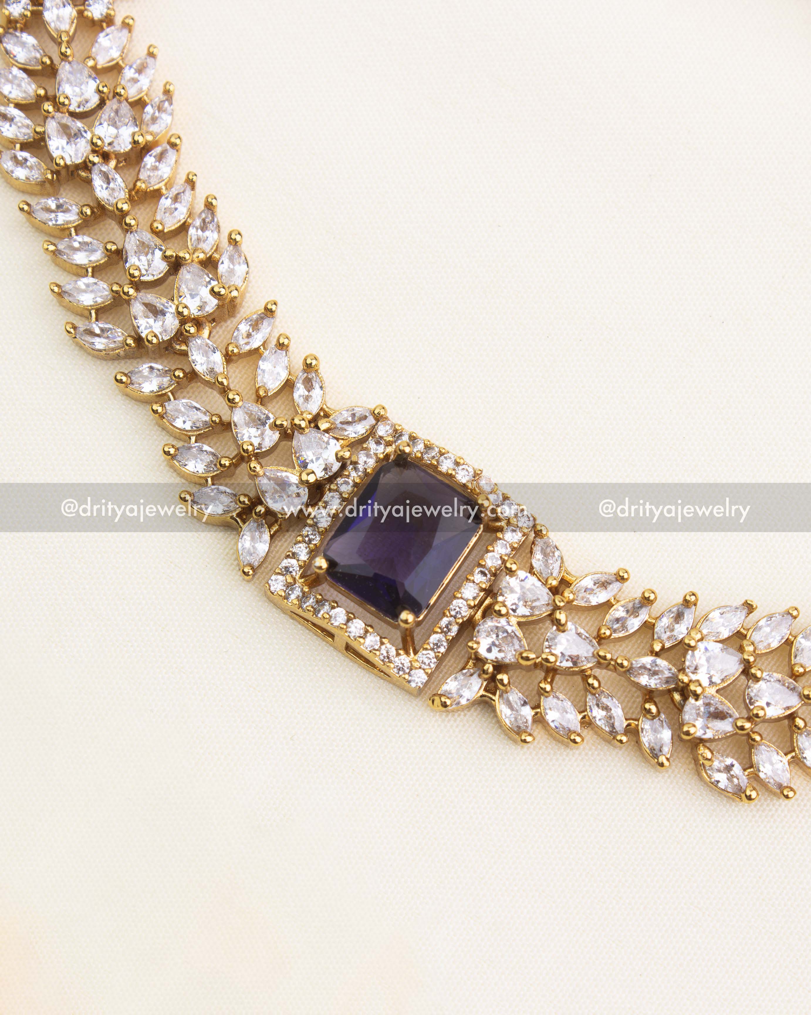 Close-up of royal purple stone bordered by micro CZs in a floral-inspired necklace design.