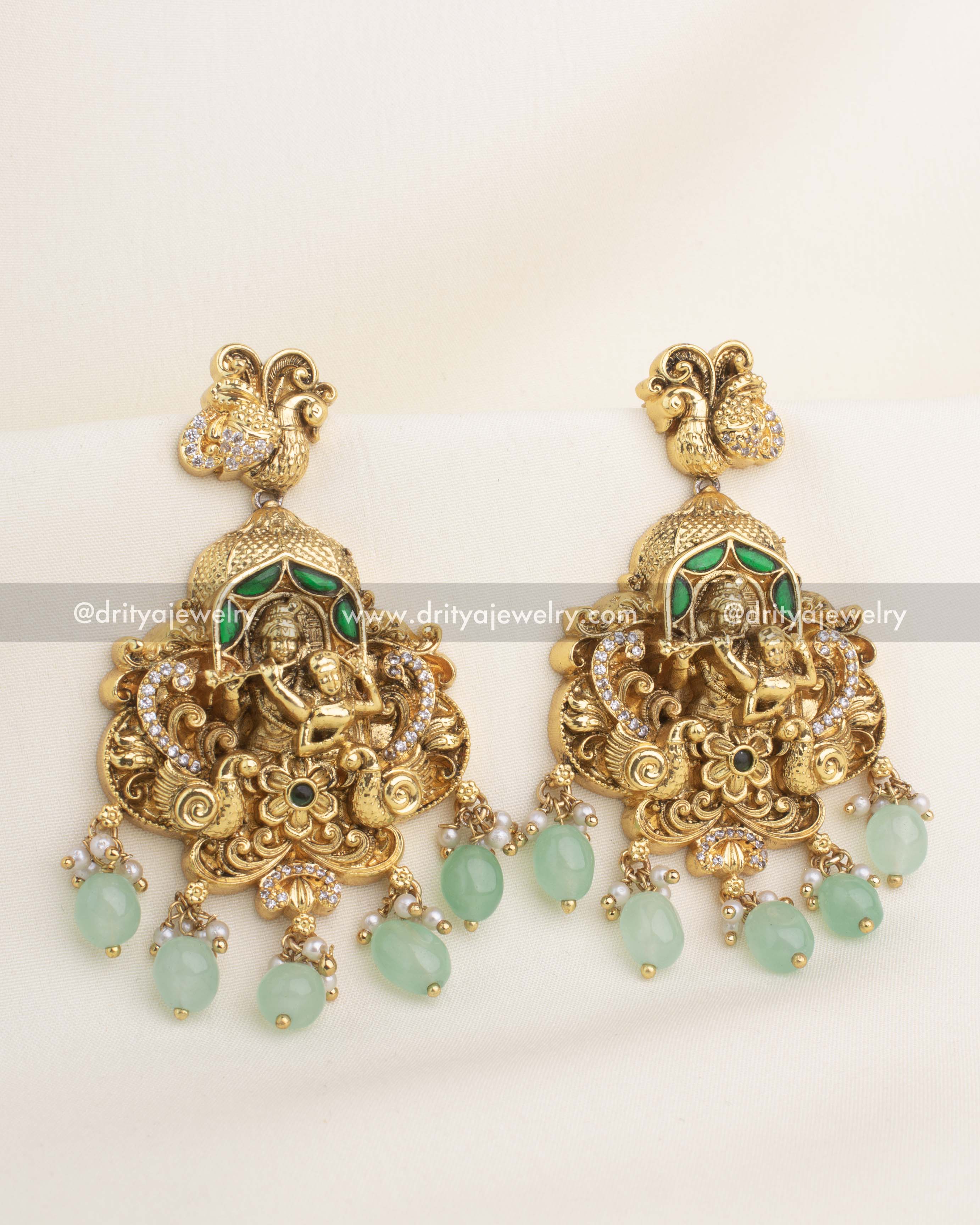 Gold temple earrings with Radha Krishna motif, peacock top, CZ stones, and mint-green bead and pearl hangings.