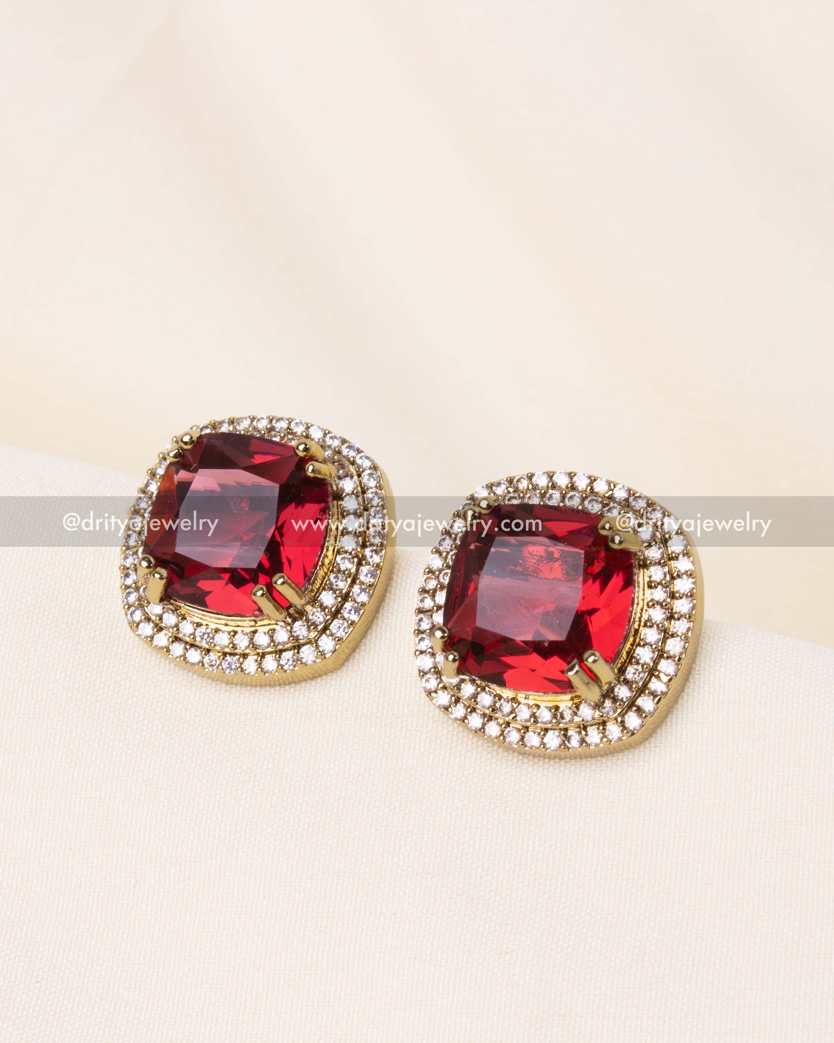 Cushion-cut red gemstone earrings bordered by AD stones, perfect for ethnic and contemporary styling.