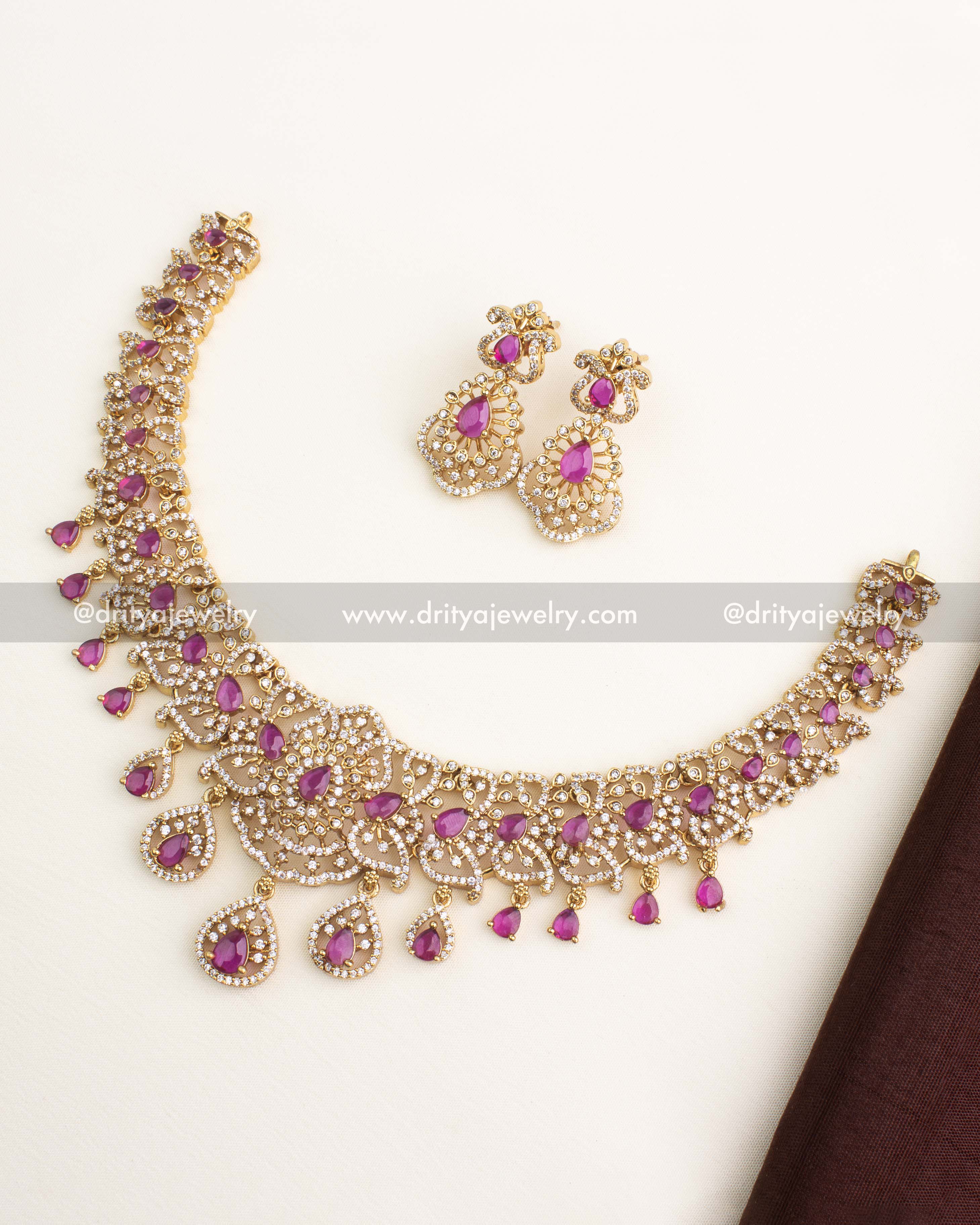 Short necklace set with ruby pear-shaped stones, gold finish, CZ layering, and matching earrings