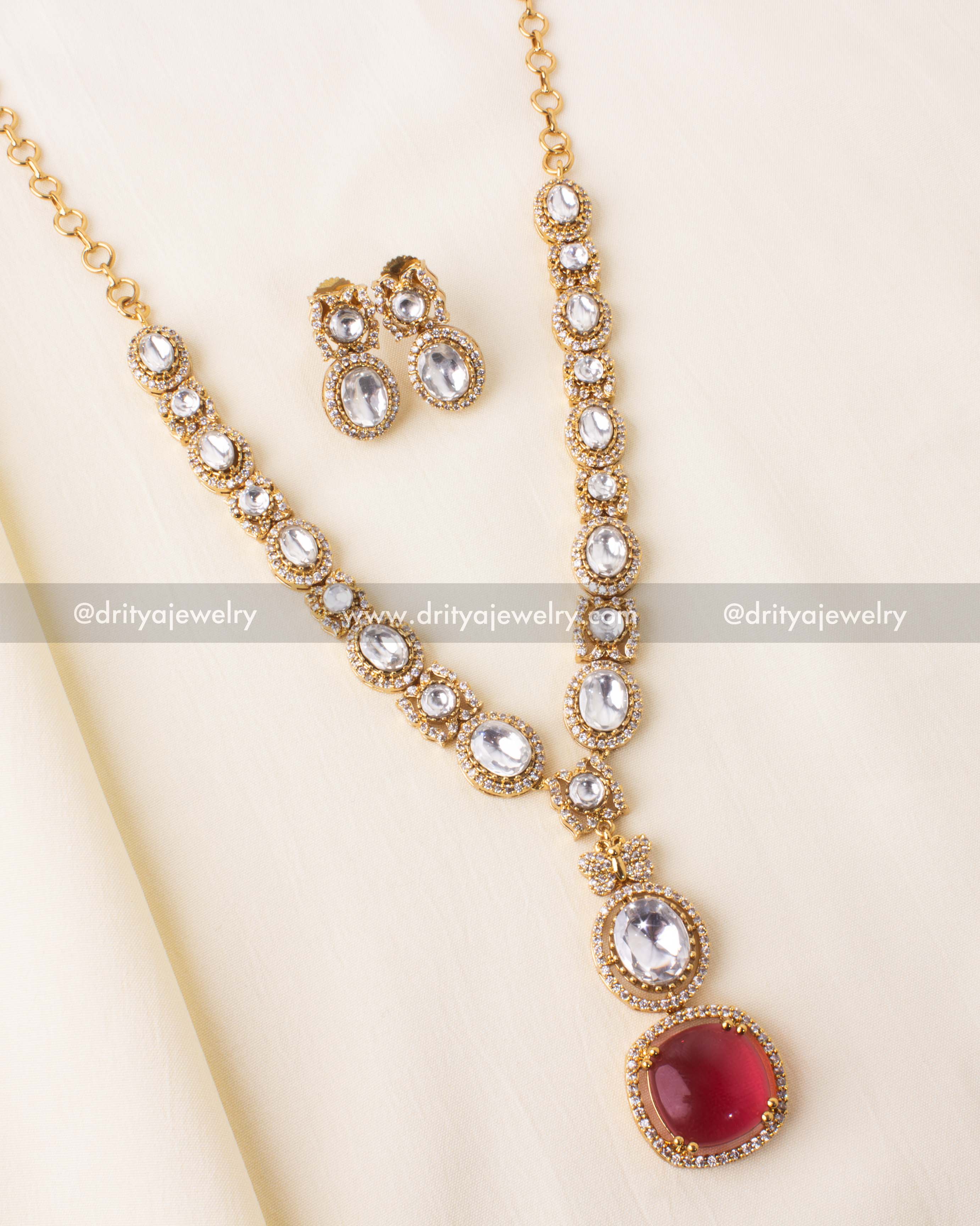 Gold-plated kundan necklace set with red pendant and matching earrings.