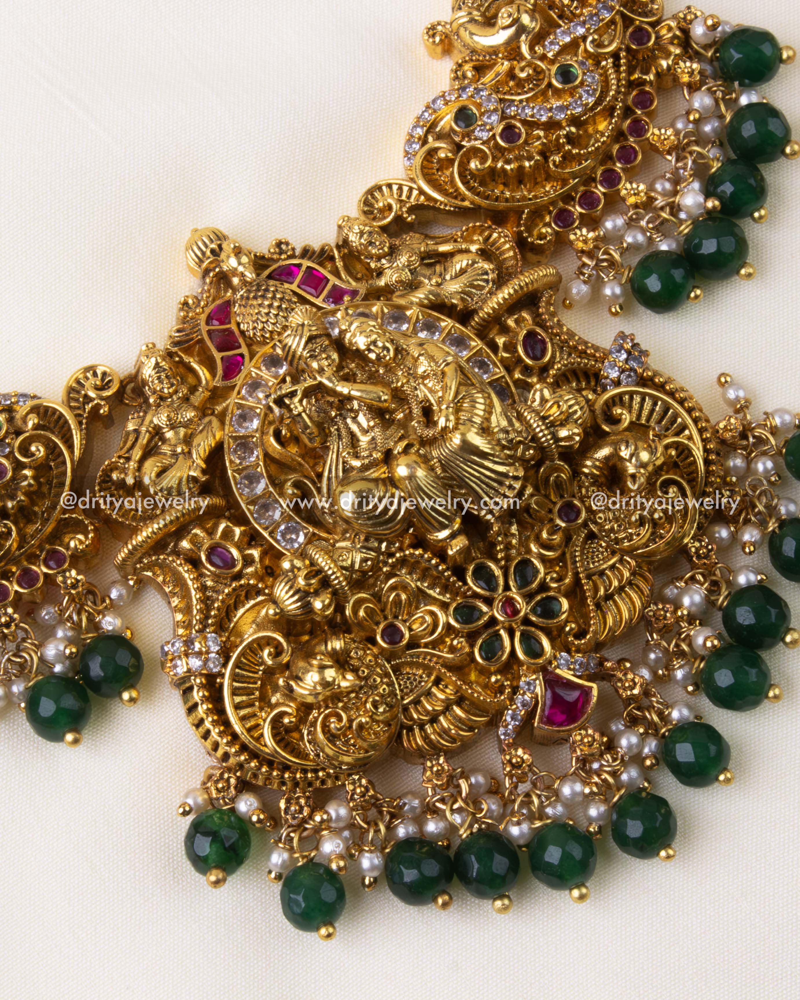 Detailed view of antique gold Lakshmi pendant with green beads and peacock motifs.