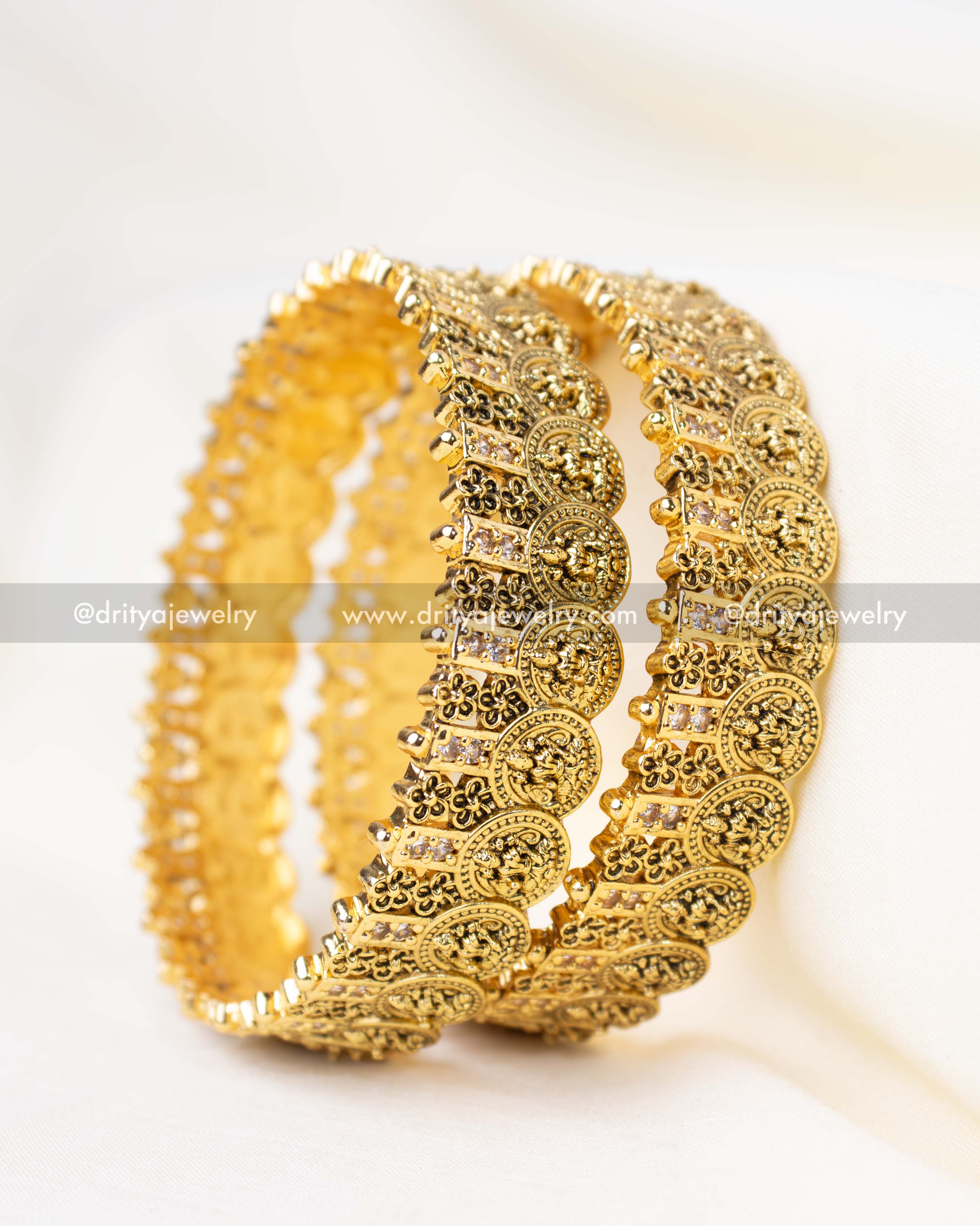 A pair of antique gold-plated bangles showcasing fine Nakshi craftsmanship with Lakshmi engravings.
