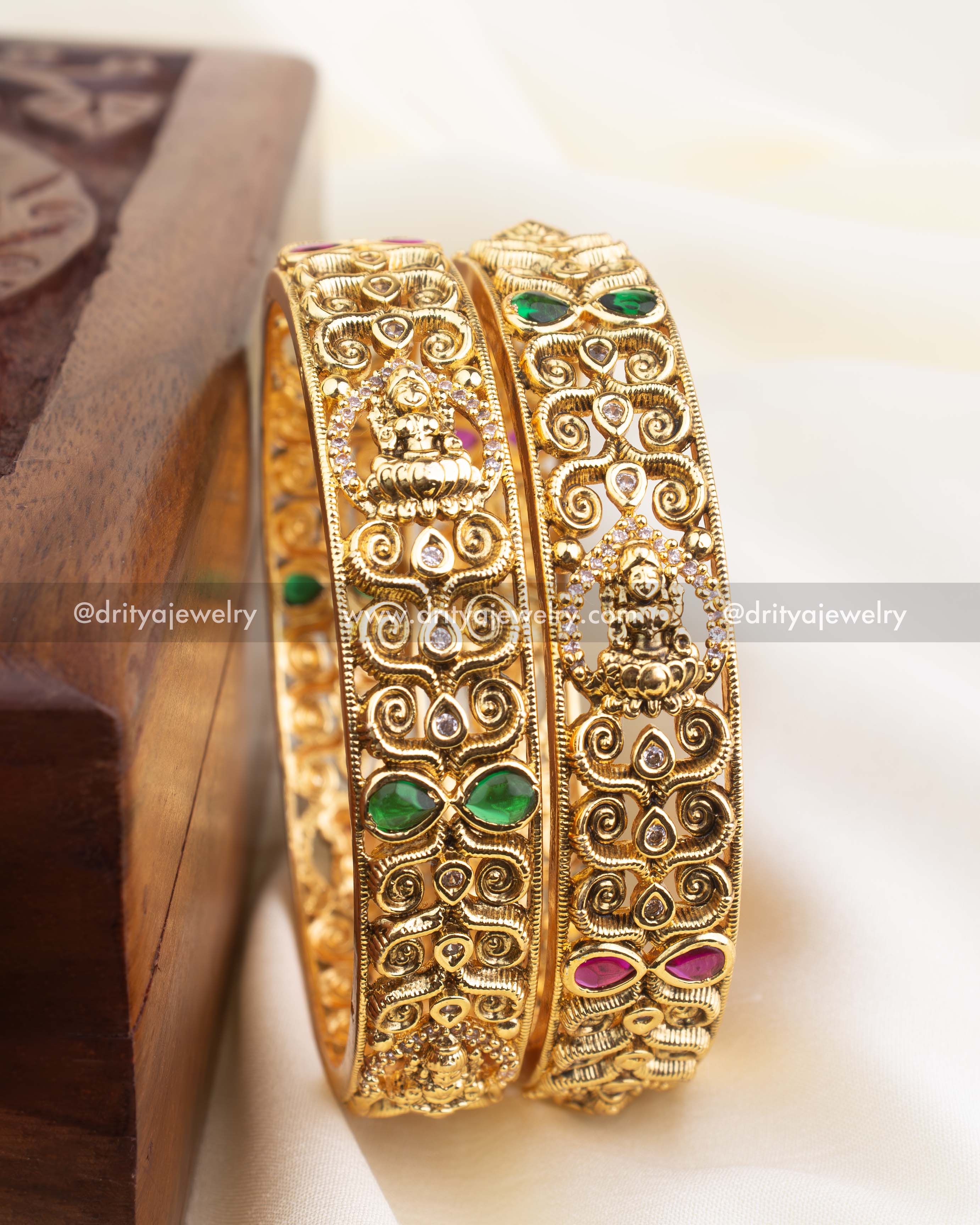 Side angle showing temple-style craftsmanship and embossed goddess motif on antique gold bangle.