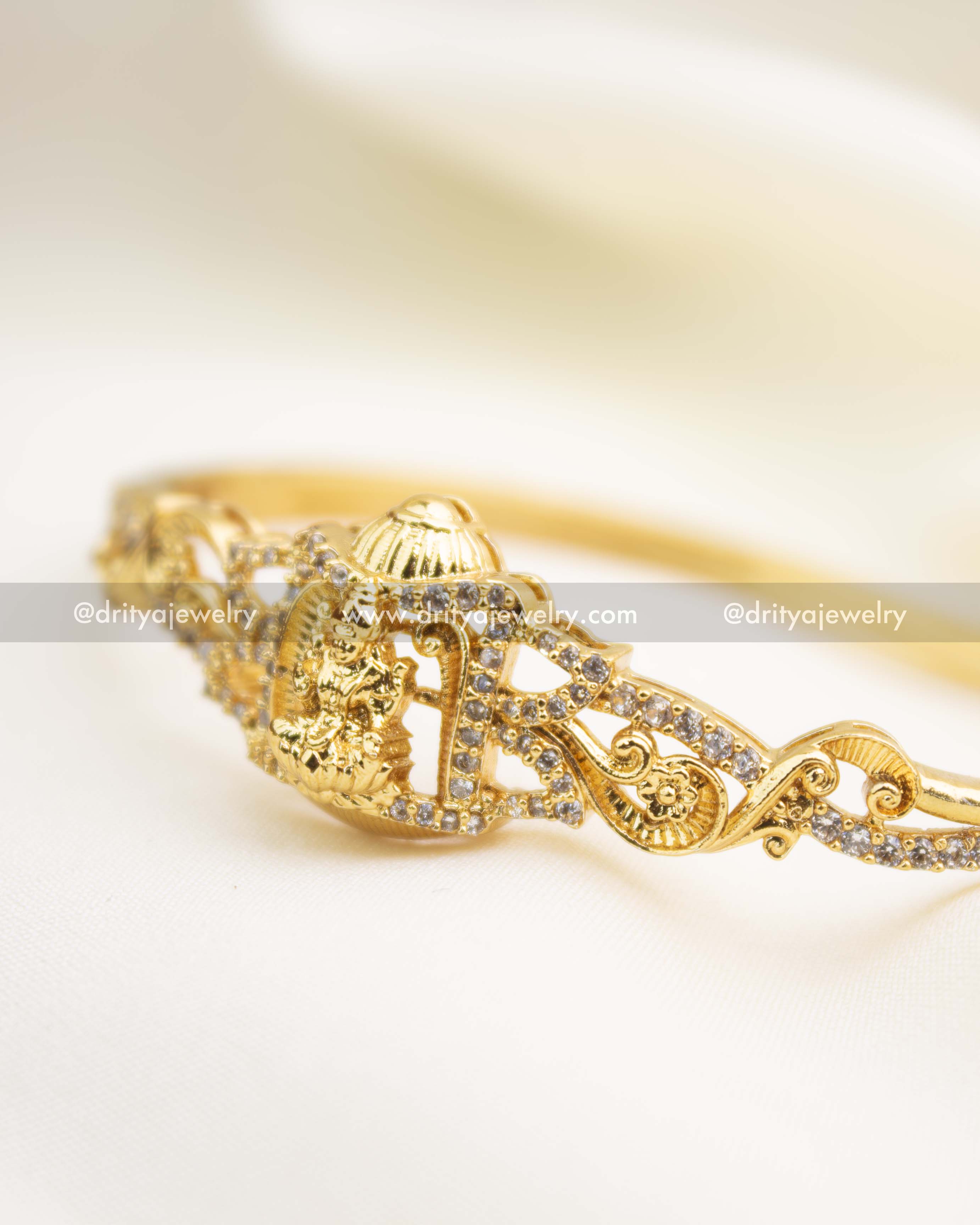Gold temple kada with intricate scrollwork and sparkling CZ embellishments.