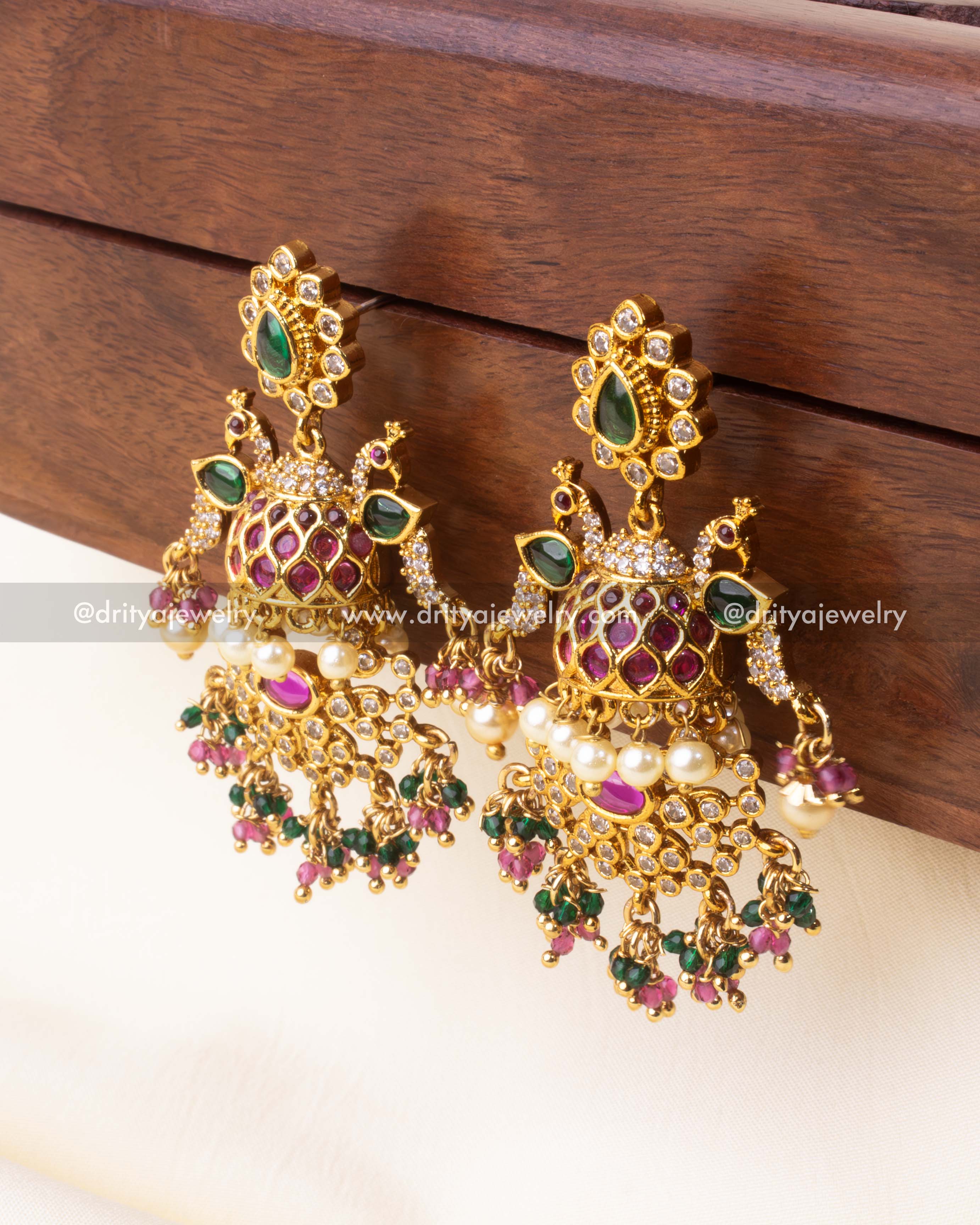 Detailed angled view of premium gold Jhumka earrings with intricate enamel and bead design.
