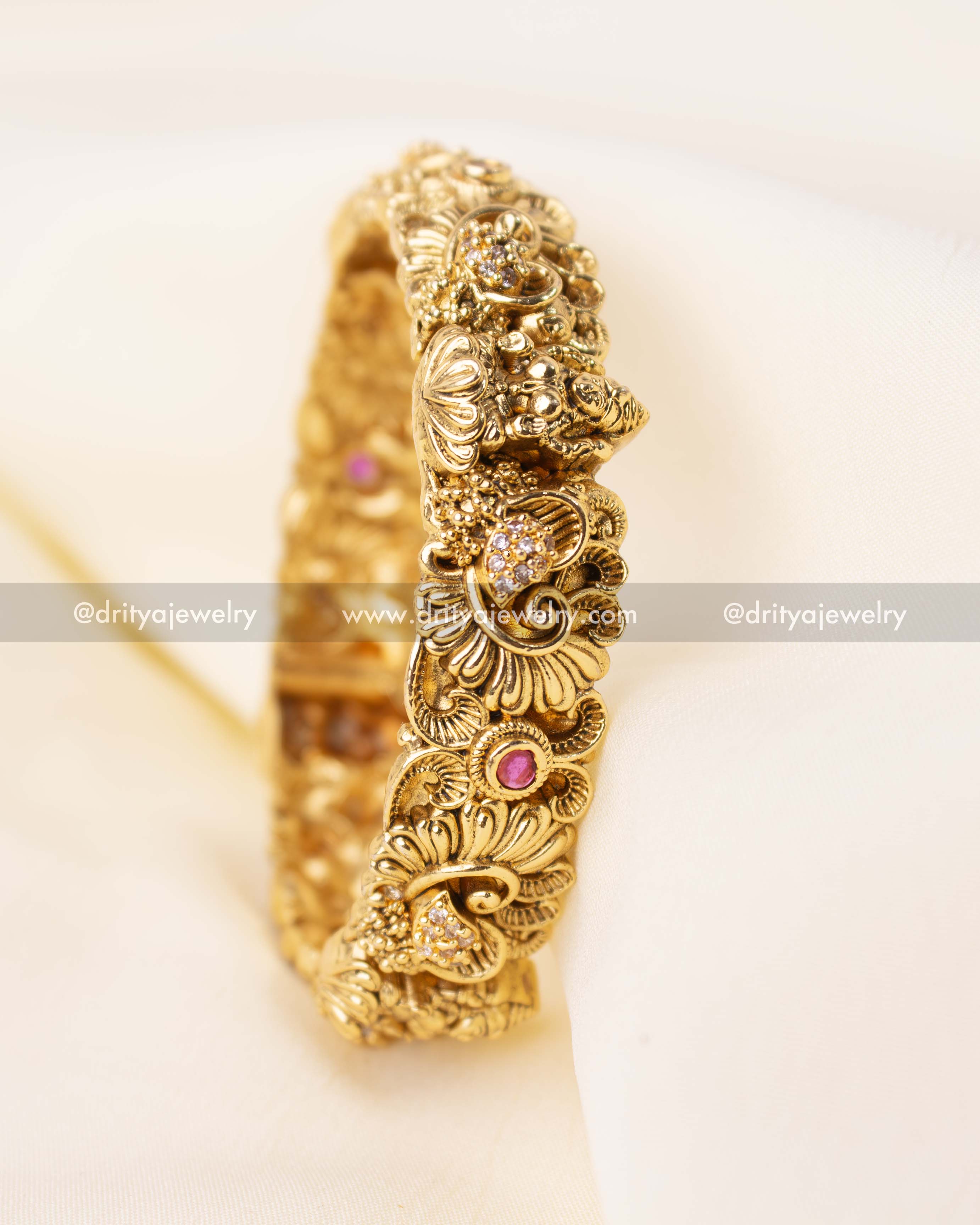 Side view of single openable Nakshi bangle with floral motifs and pink center stone.