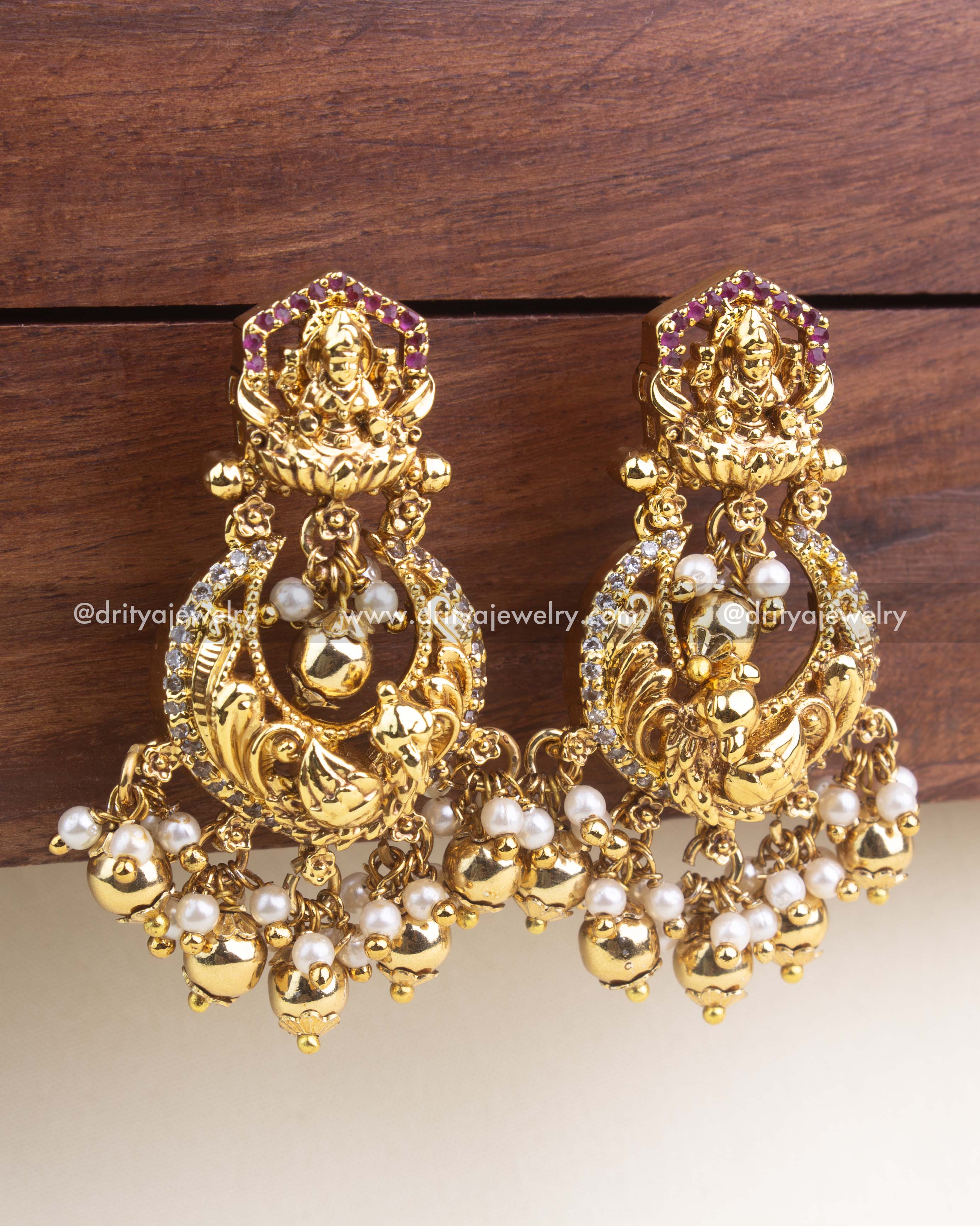 Intricate Lakshmi and peacock design chandbali earrings with gold polish and pearl drops.