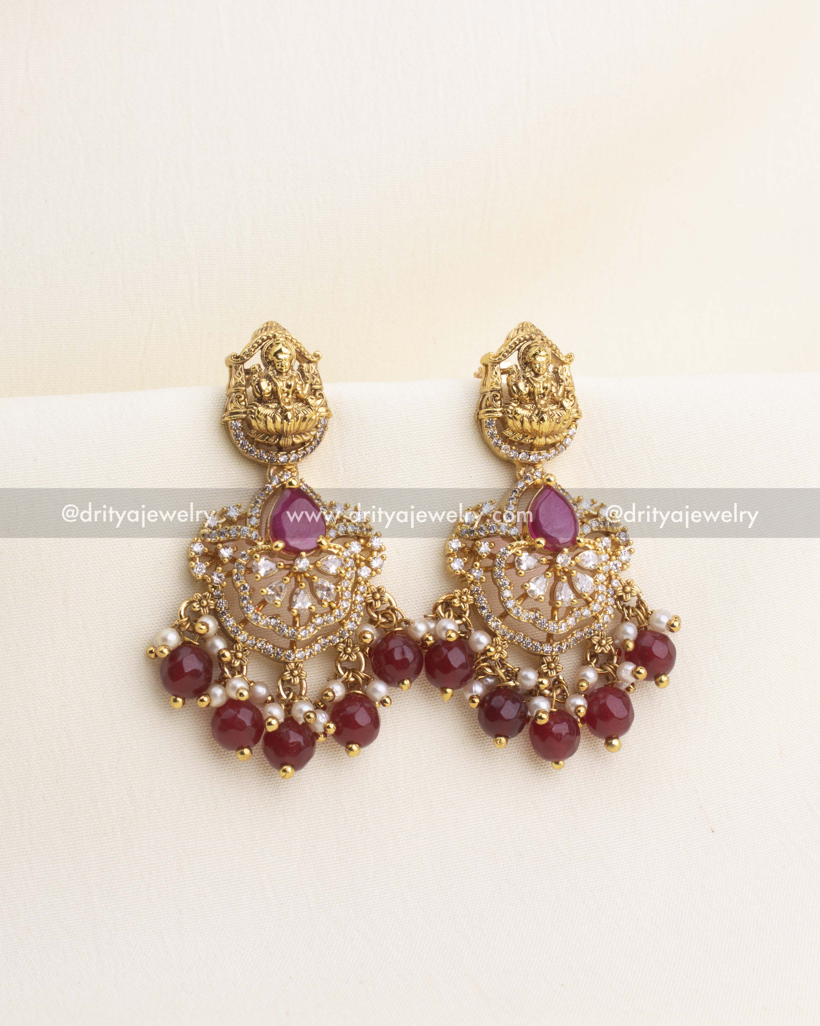 Ruby red temple earrings with CZ work, Lakshmi idol top, and pearl-bead detailing.