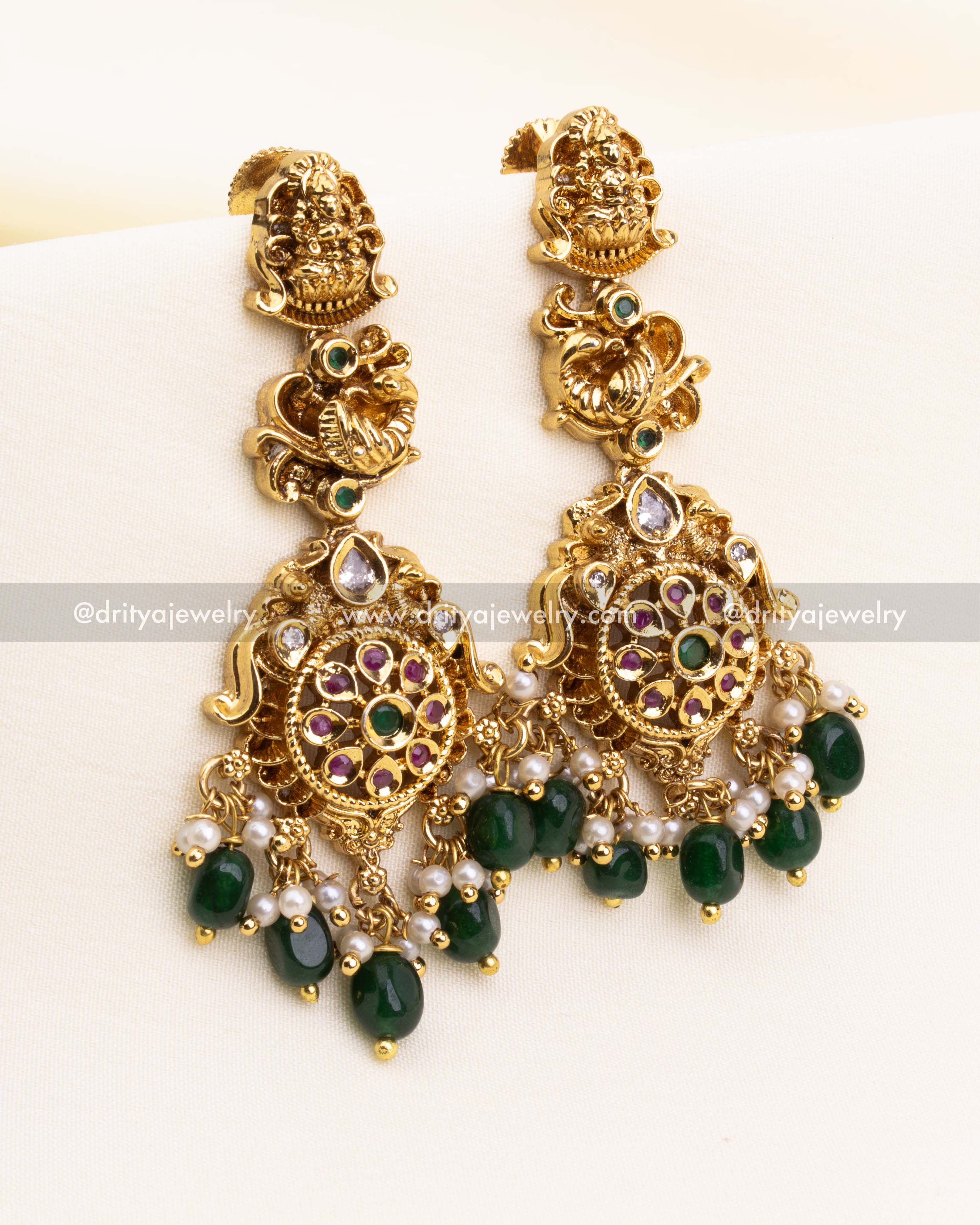 Traditional temple jhumka earrings with peacock motifs, CZ stones, and hanging green beads.