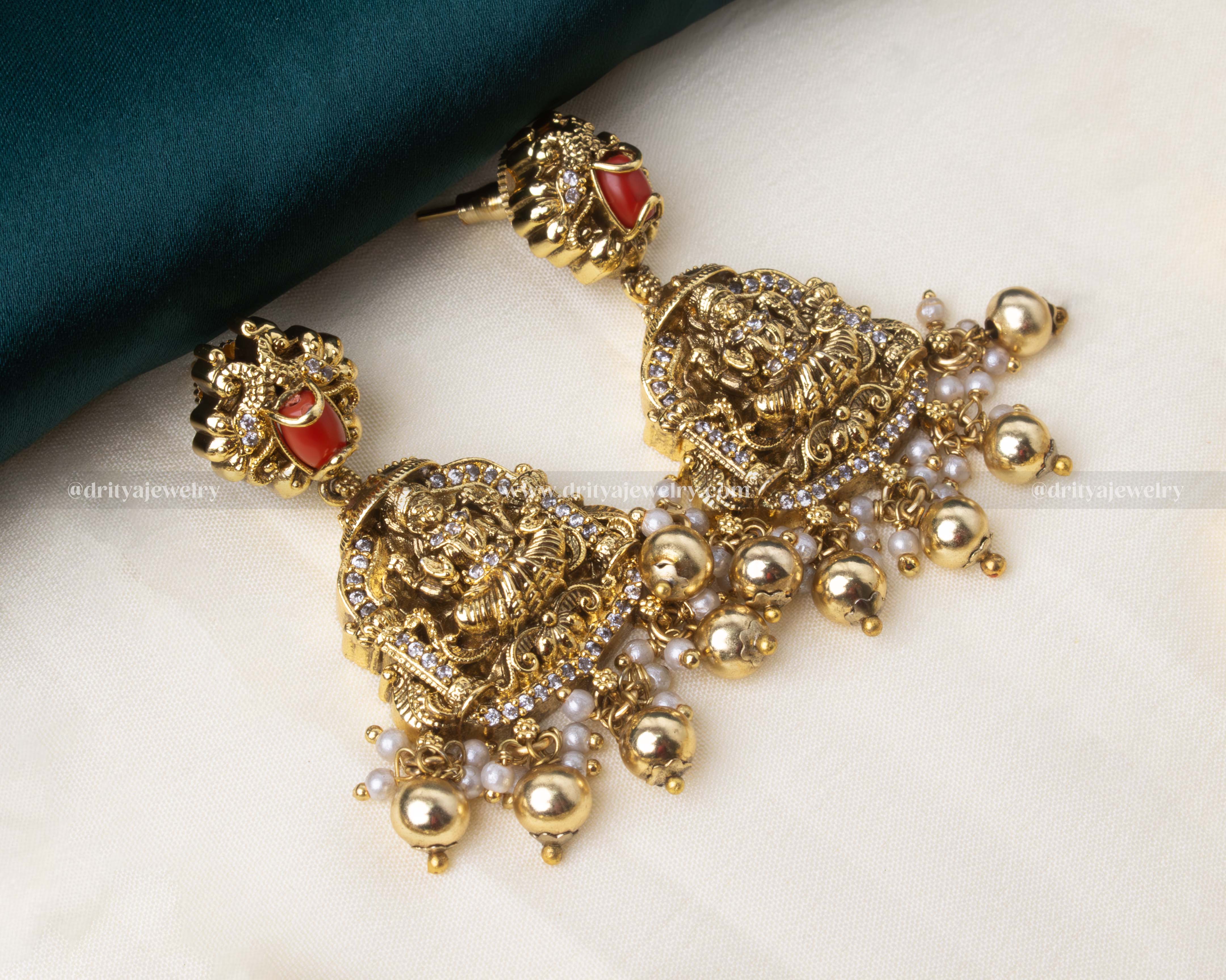 Matching temple-style earrings with red accents and pearl embellishments.