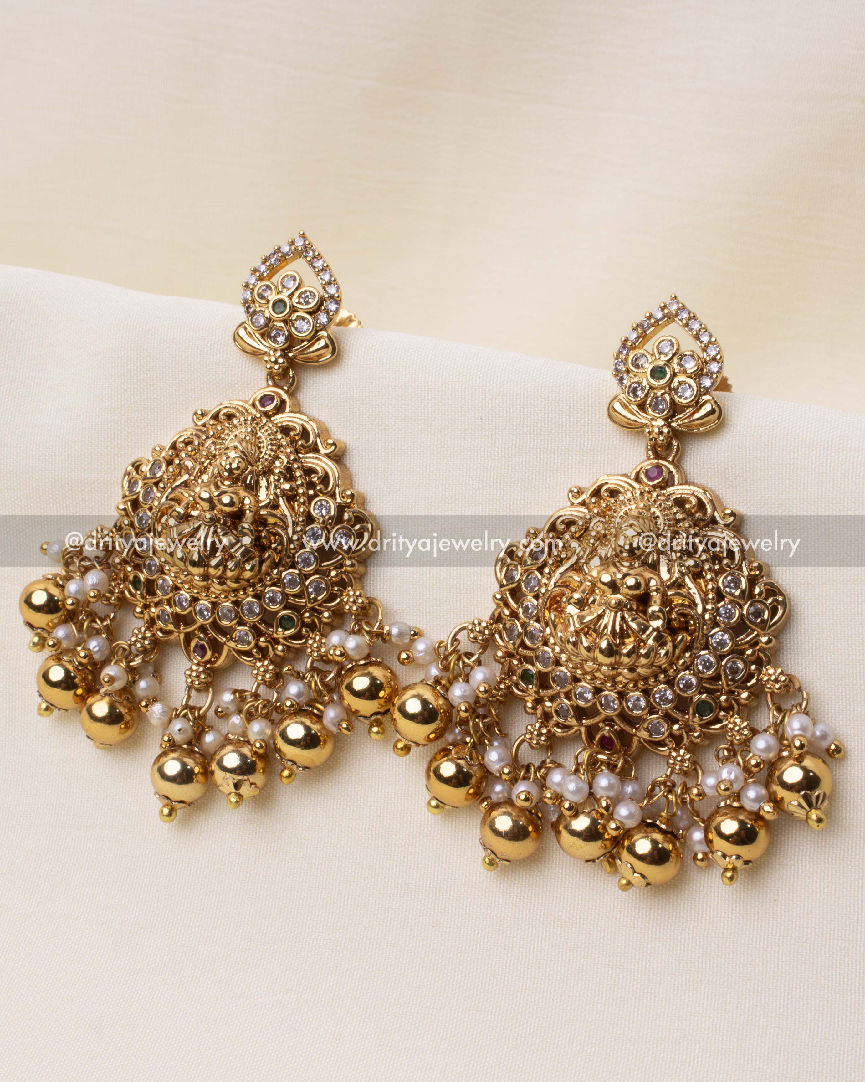 Exquisite Nakshi-style temple earrings with intricate detailing, white stones, and pearl danglers.