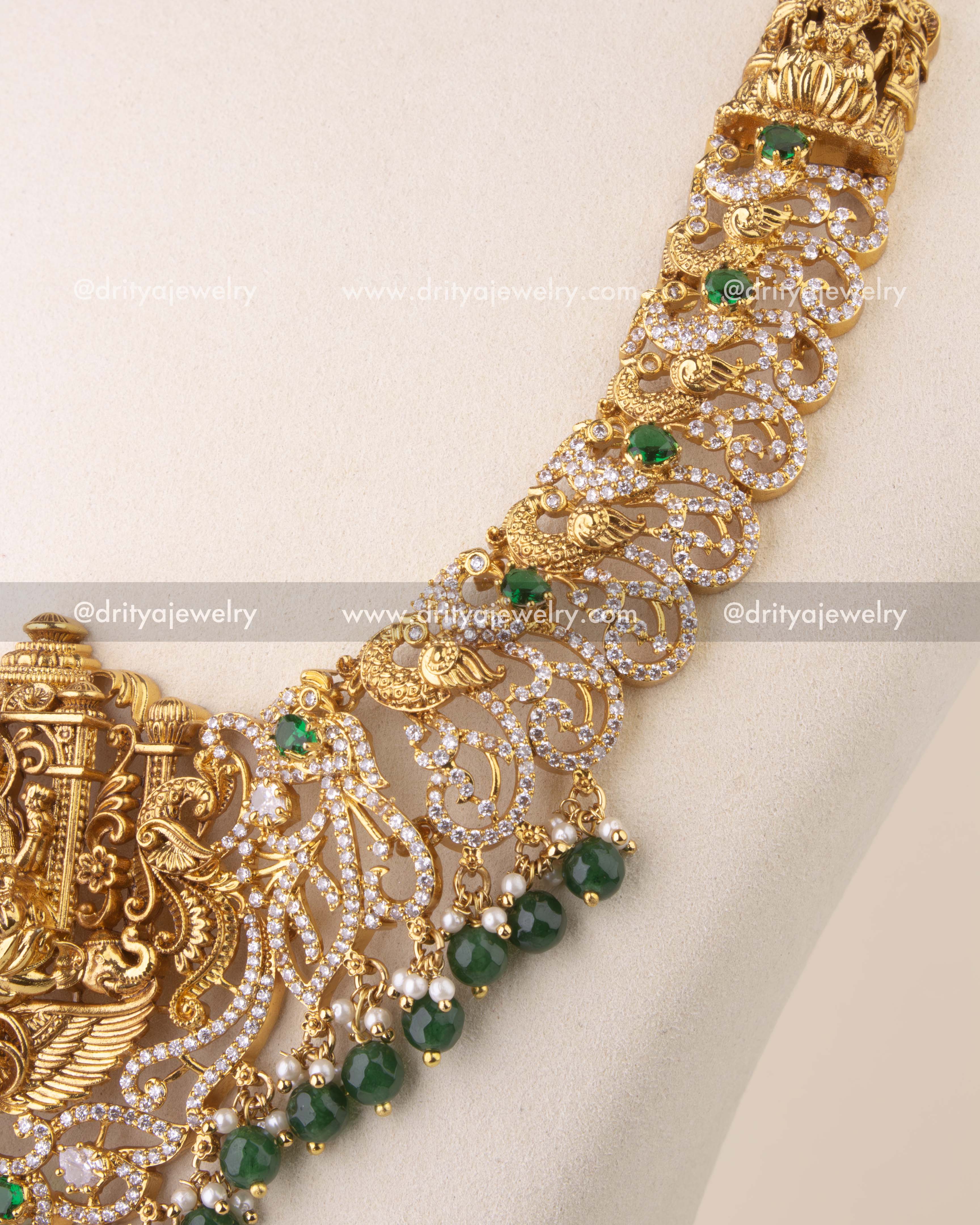 Close-up of Nakshi temple necklace with intricate peacock motifs and faceted green bead hangings.