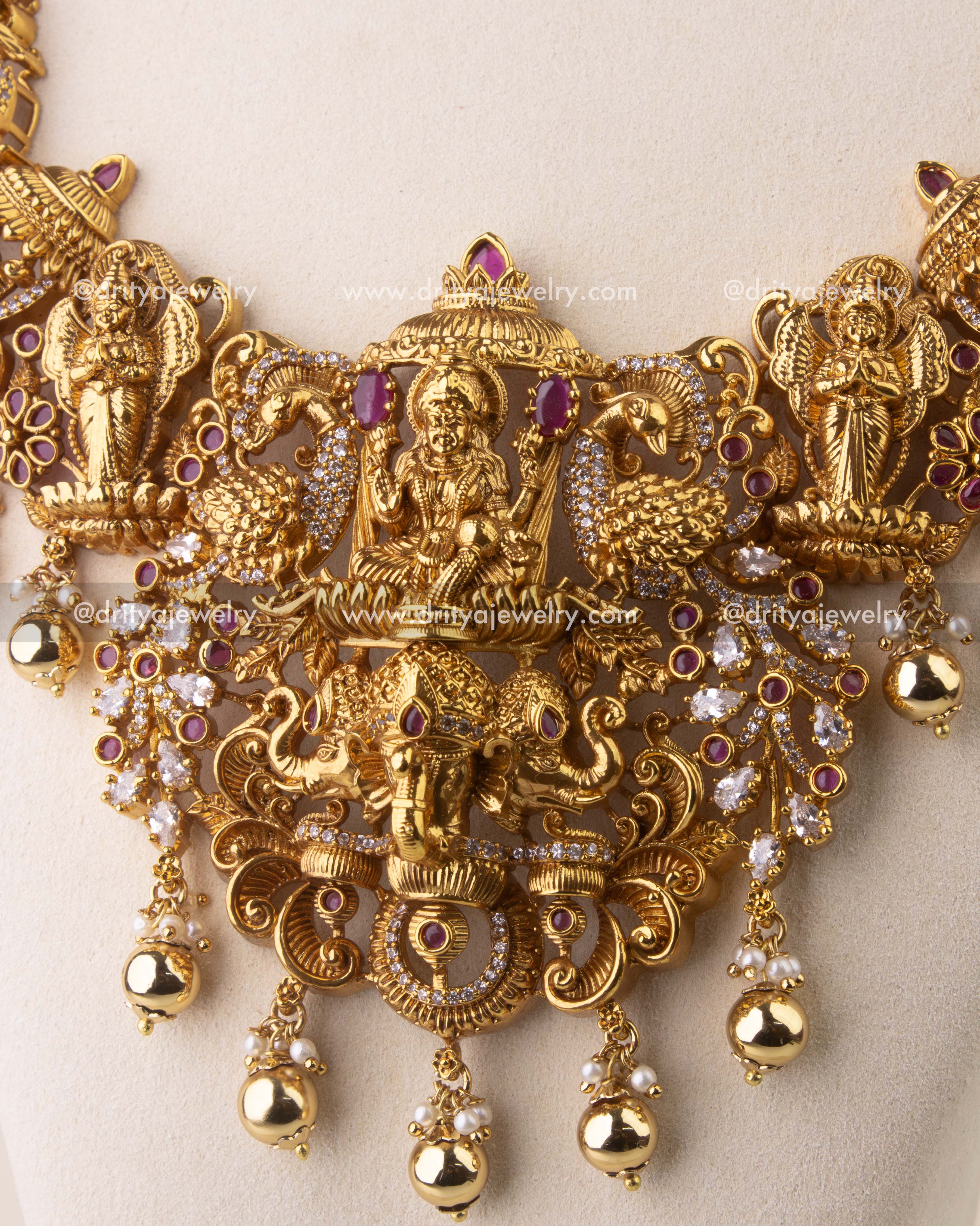 Close-up of antique temple necklace with peacock, elephant, and deity engravings embellished with Kemp stones.