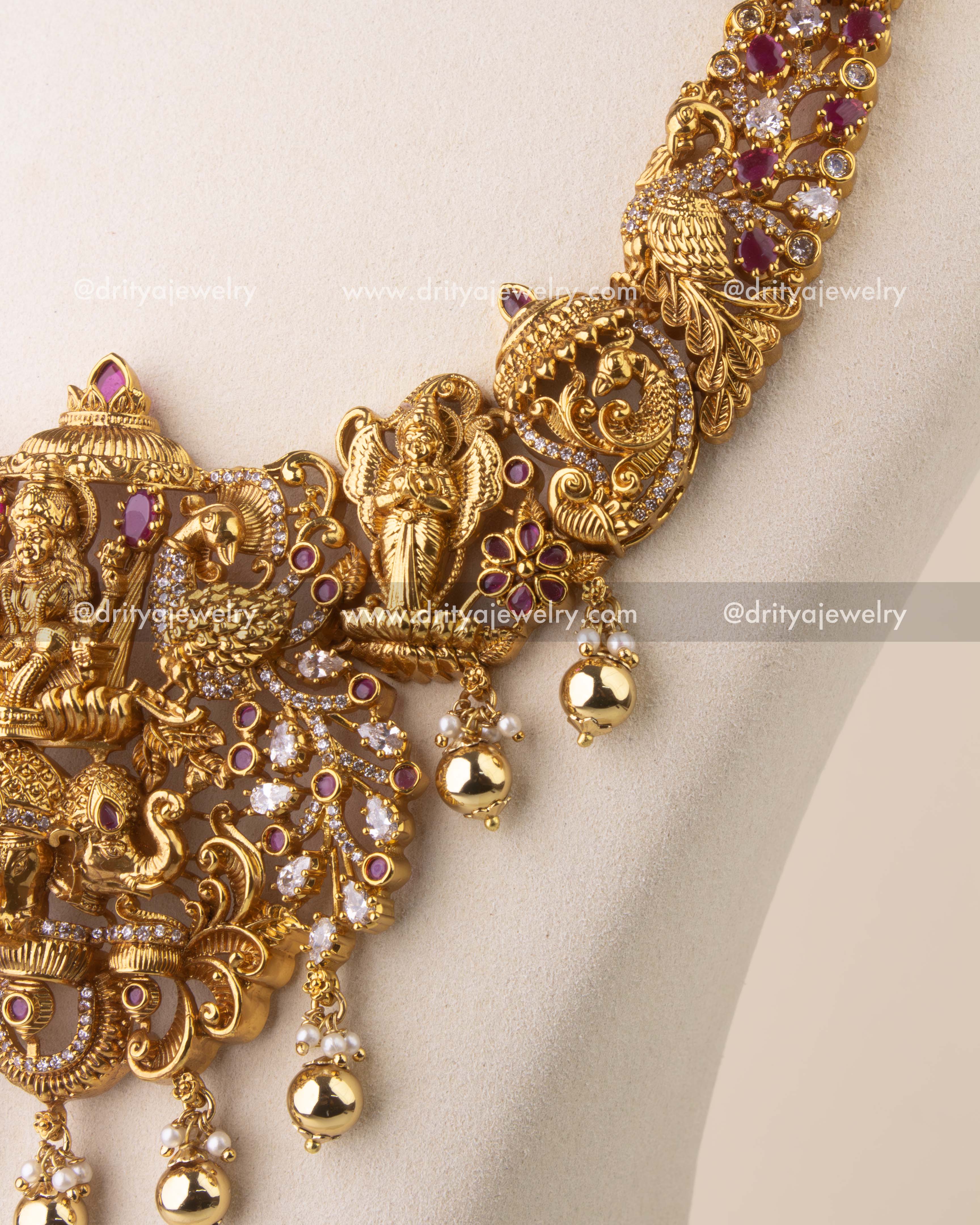 Close-up of antique temple necklace with peacock, elephant, and deity engravings embellished with Kemp stones