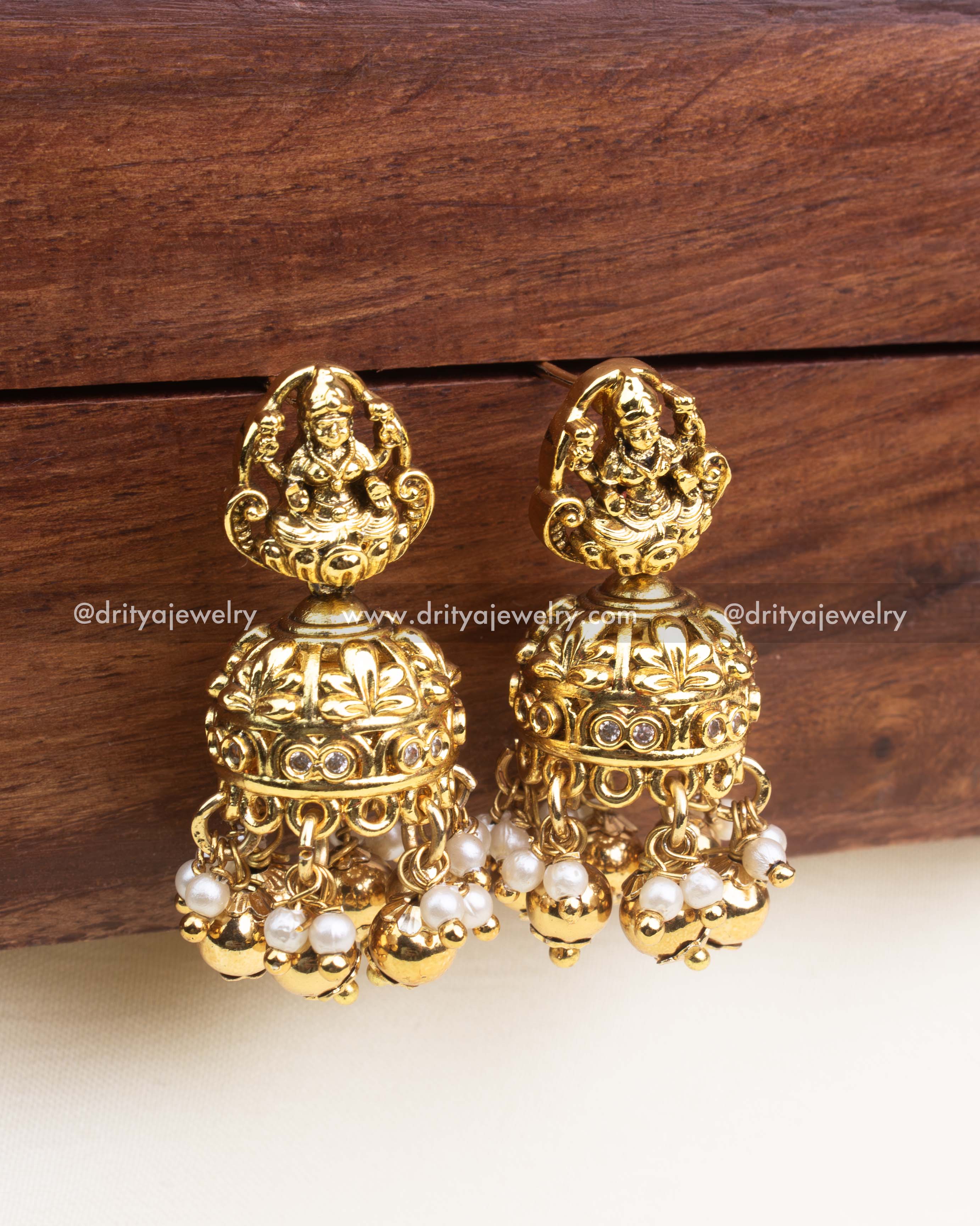 Antique gold jhumka earrings featuring Lakshmi motifs, pearls, and gold bead danglings.